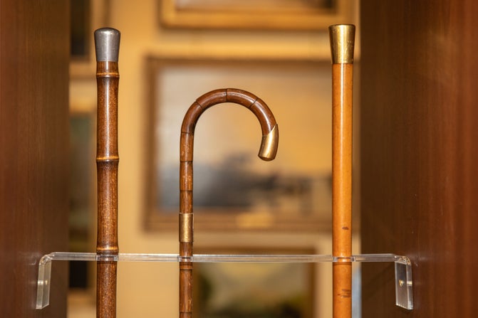 Close up of three of Lord Fairhaven's wooden walking sticks, first and third in a row are upside down, the middle has a curved handle.