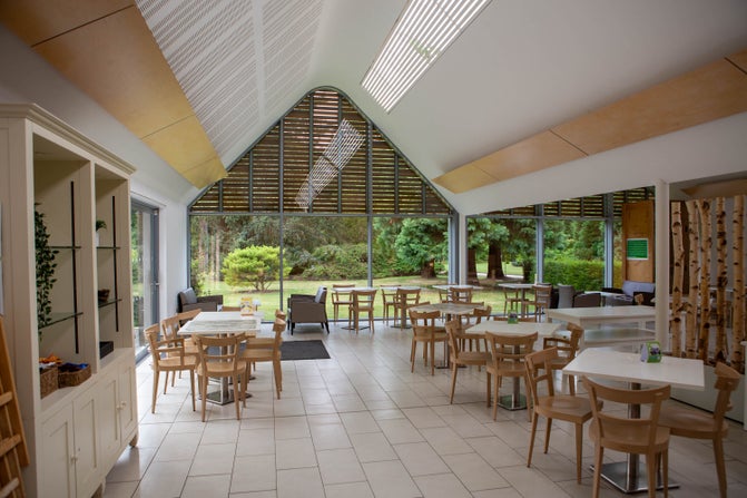 A view of Redwoods Restaurant on the inside, with white hard floors, an arched roof and square tables and chairs in the room.