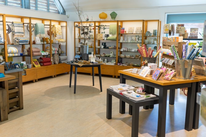 A light room with elegant shop displays on tables, stools and shelves.