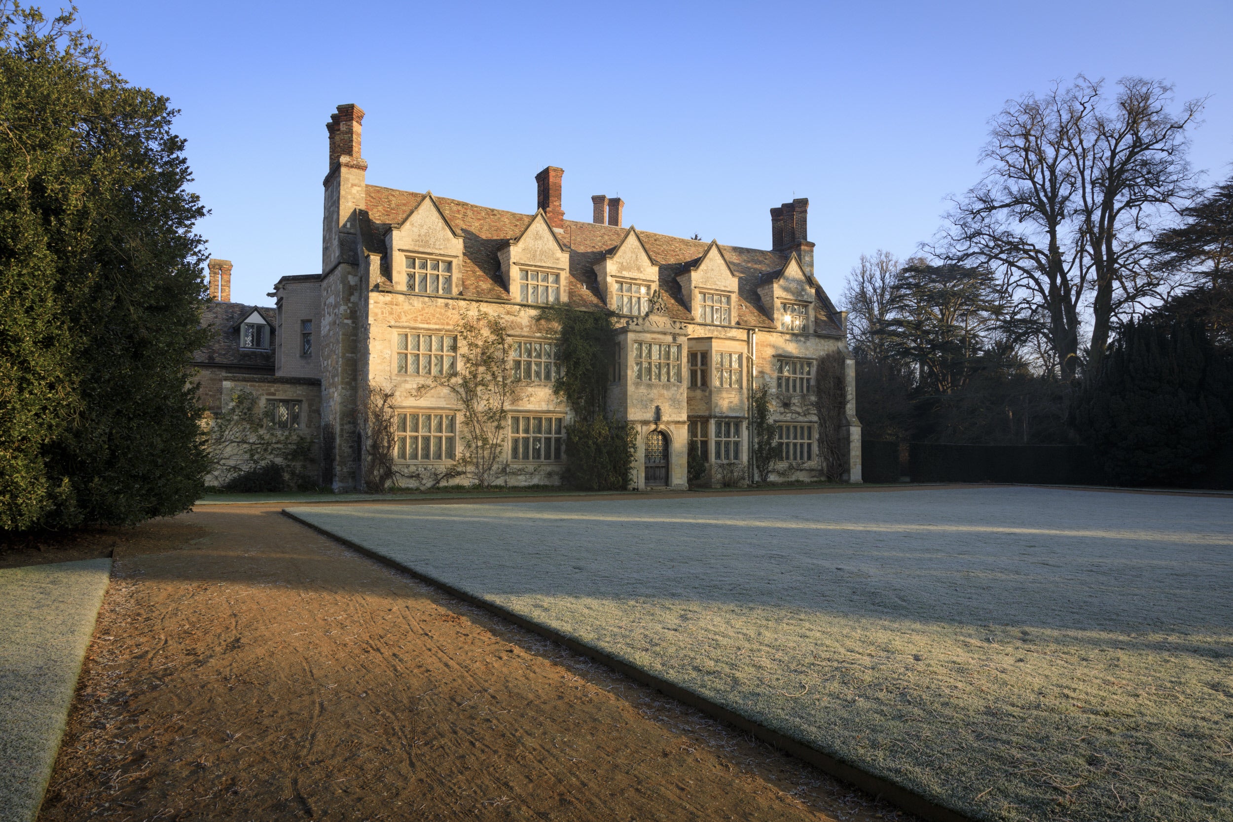 A photo of the frosty lawn in front of the house at Anglesey Abbey. Blue skies.