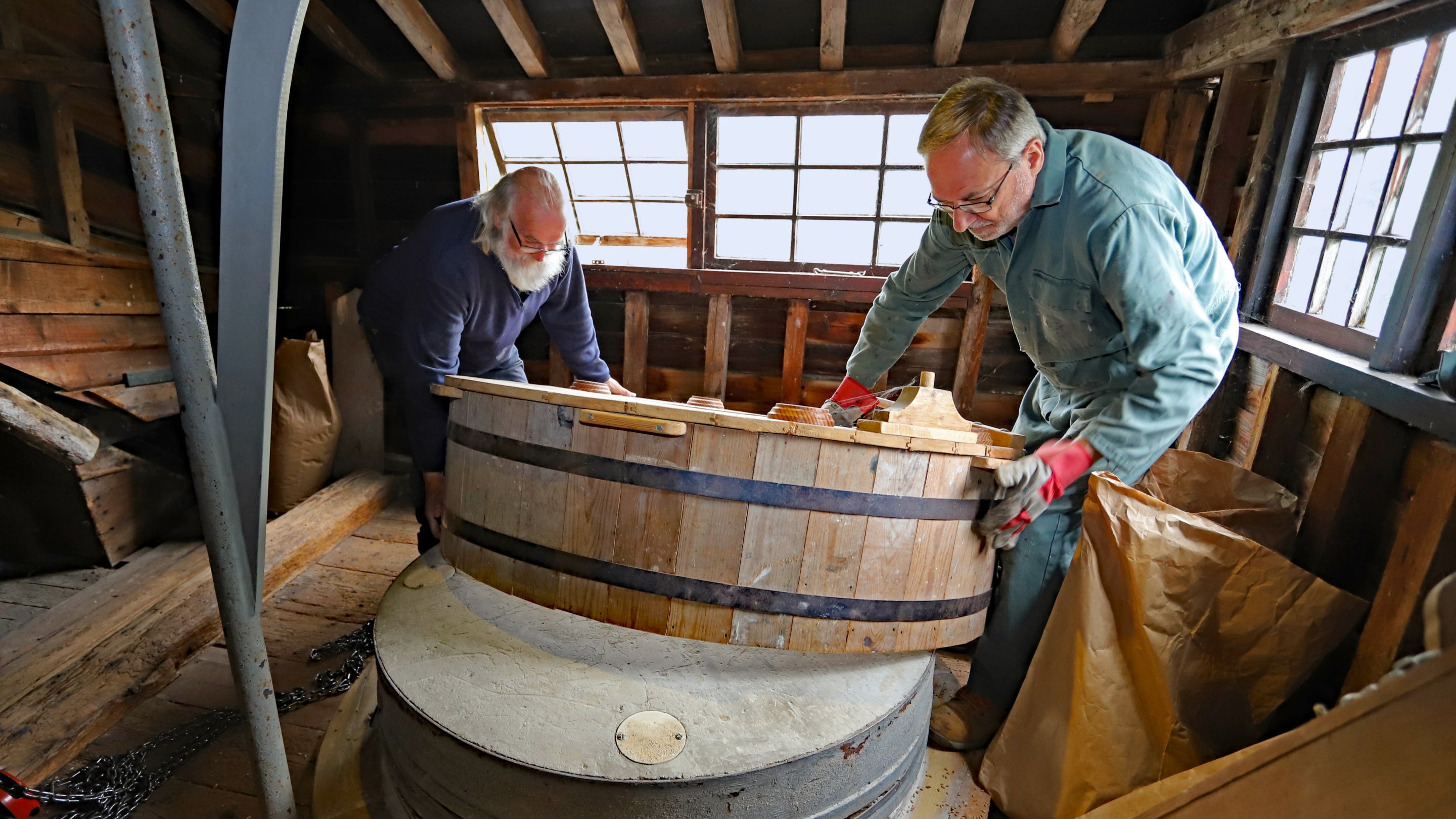 Two people working on millstone maintenance at Houghton Mill and Waterclose Meadows, Cambridgeshire.