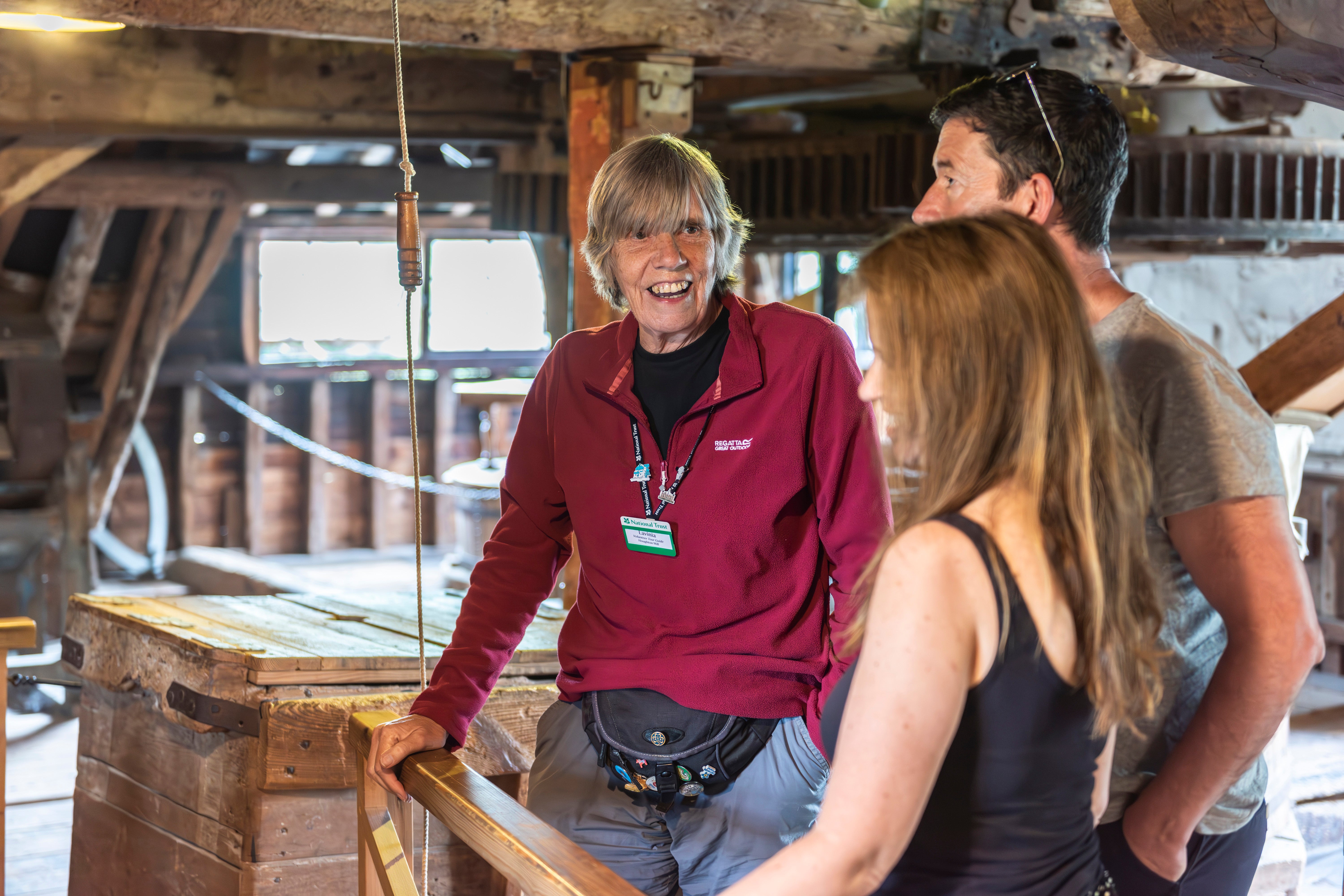 Volunteer guide talking with visitors inside Houghton Mill