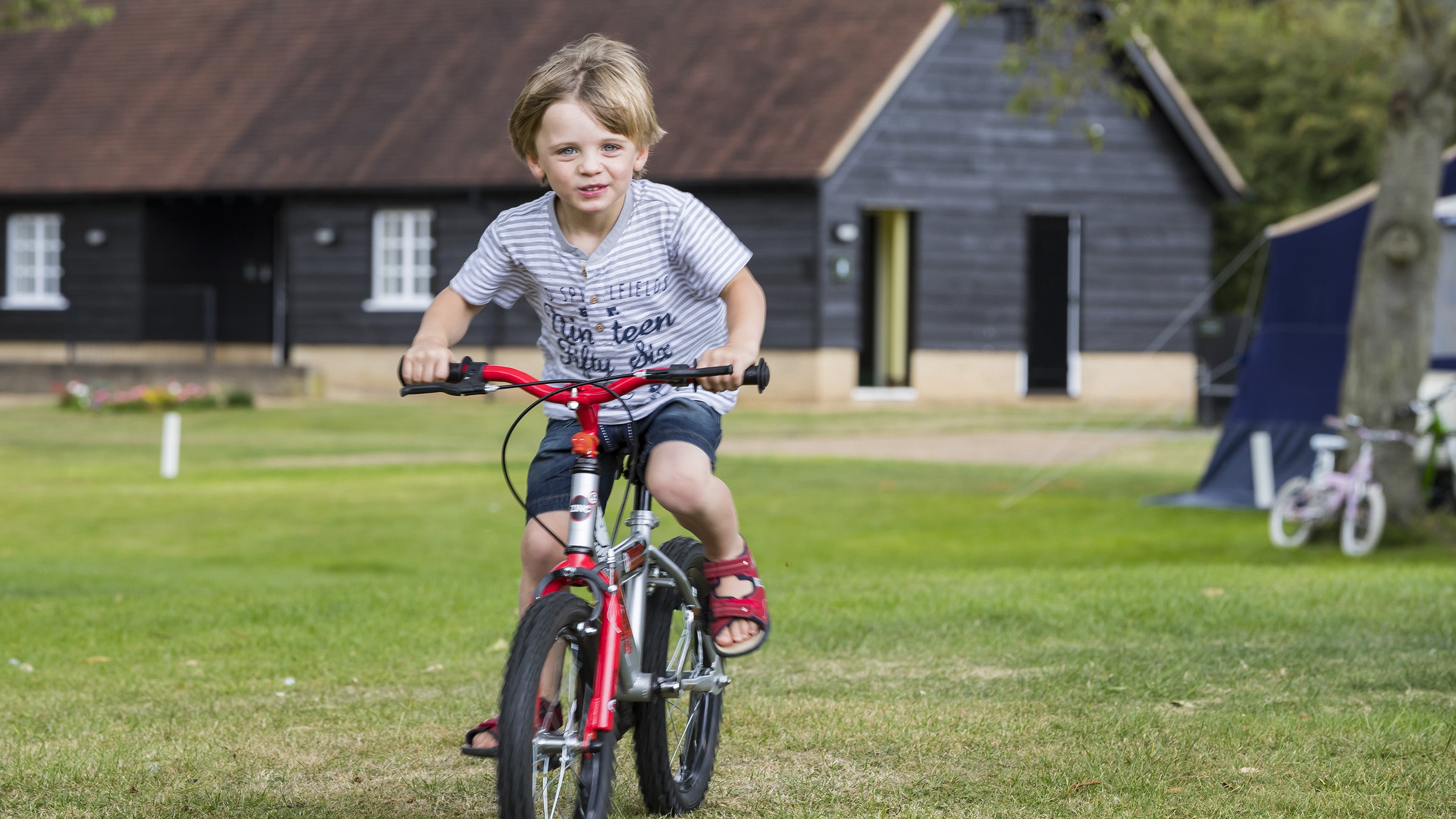 Child riding a bike on the Waterclose Meadows campsite at Houghton Mill, Cambridgeshire