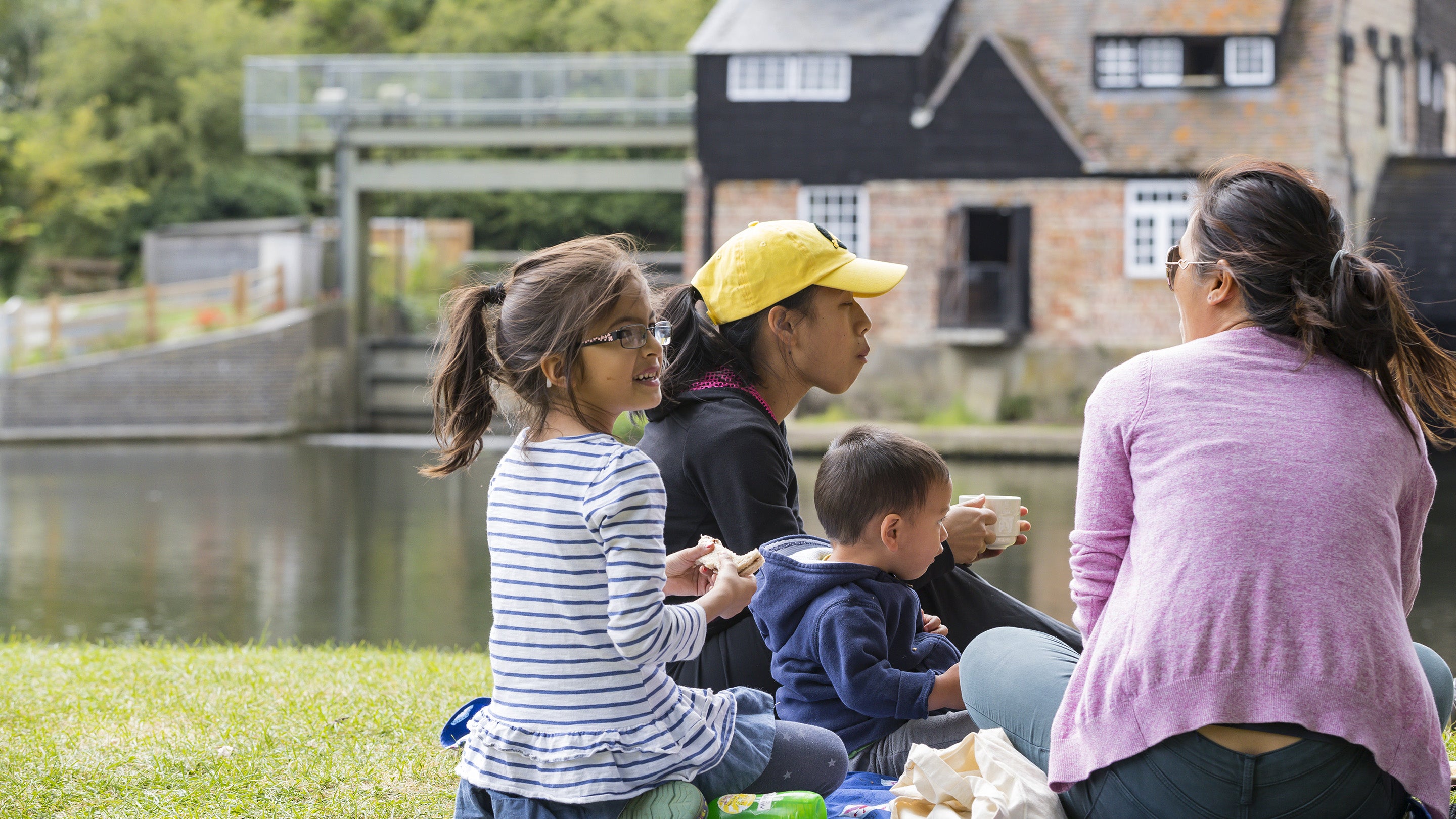 Family enjoying a picnic on the banks of the river at Houghton Mill, Cambridgeshire