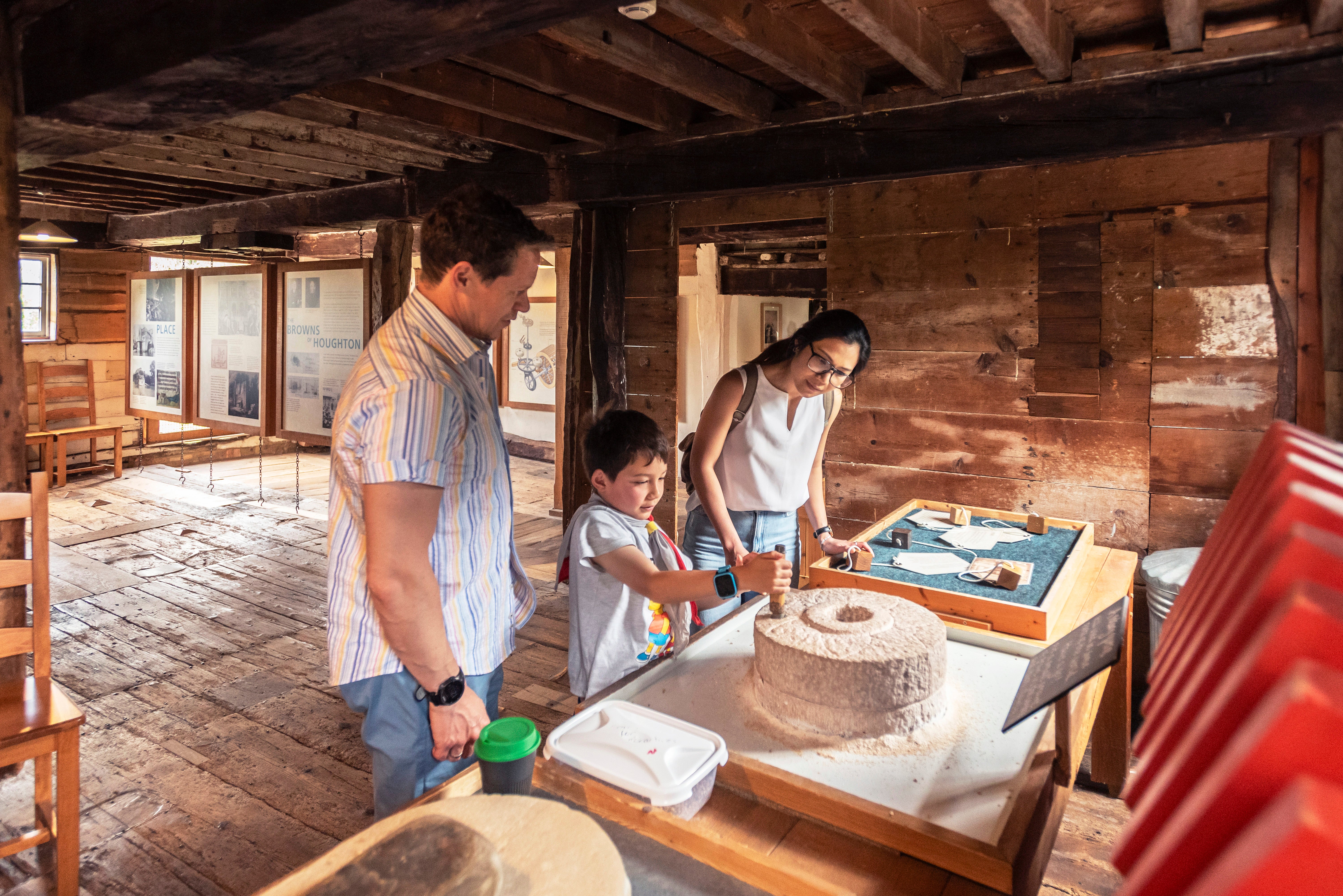Visitors milling on a hand quern inside Houghton Mill