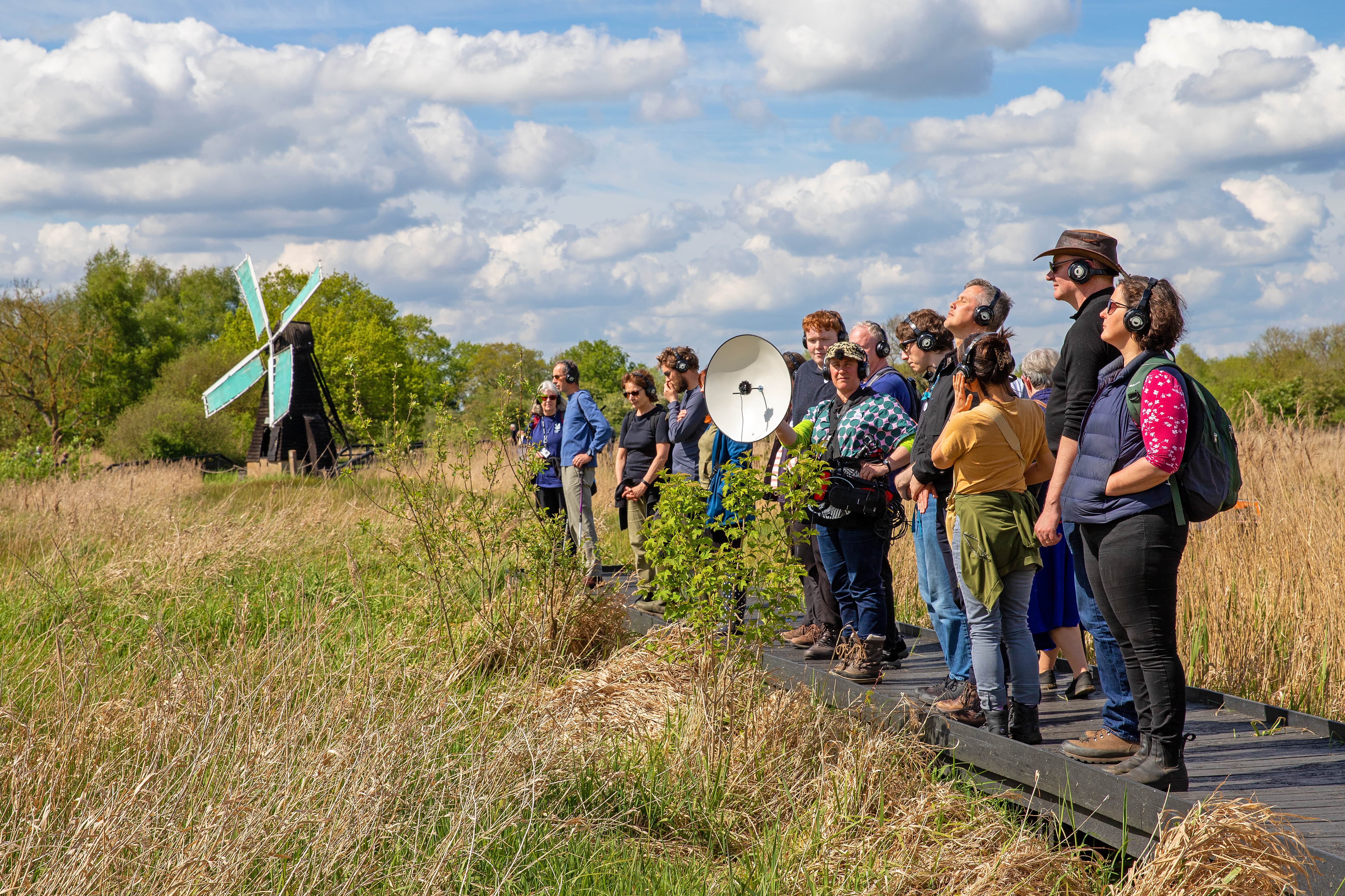 A group of visitors stood in a line listening with a microphone