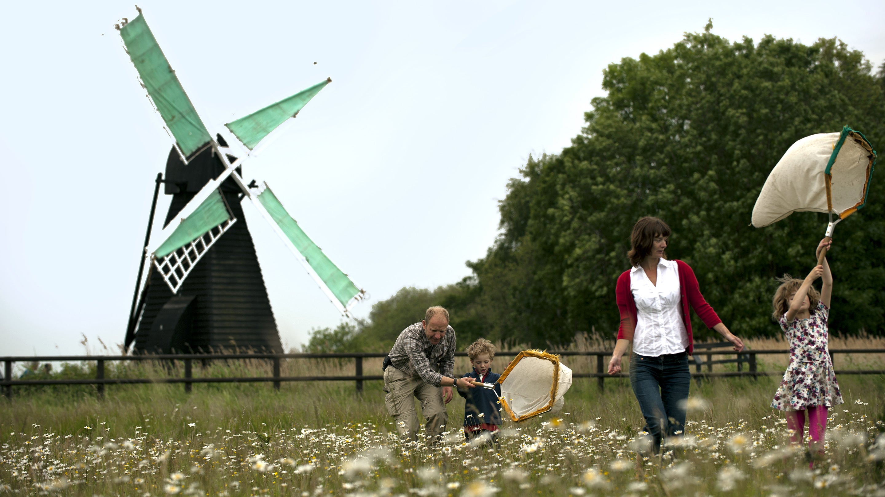 A family takes part in an insect hunt in front of a windmill at Wicken Fen National Nature Reserve, Cambridgeshire