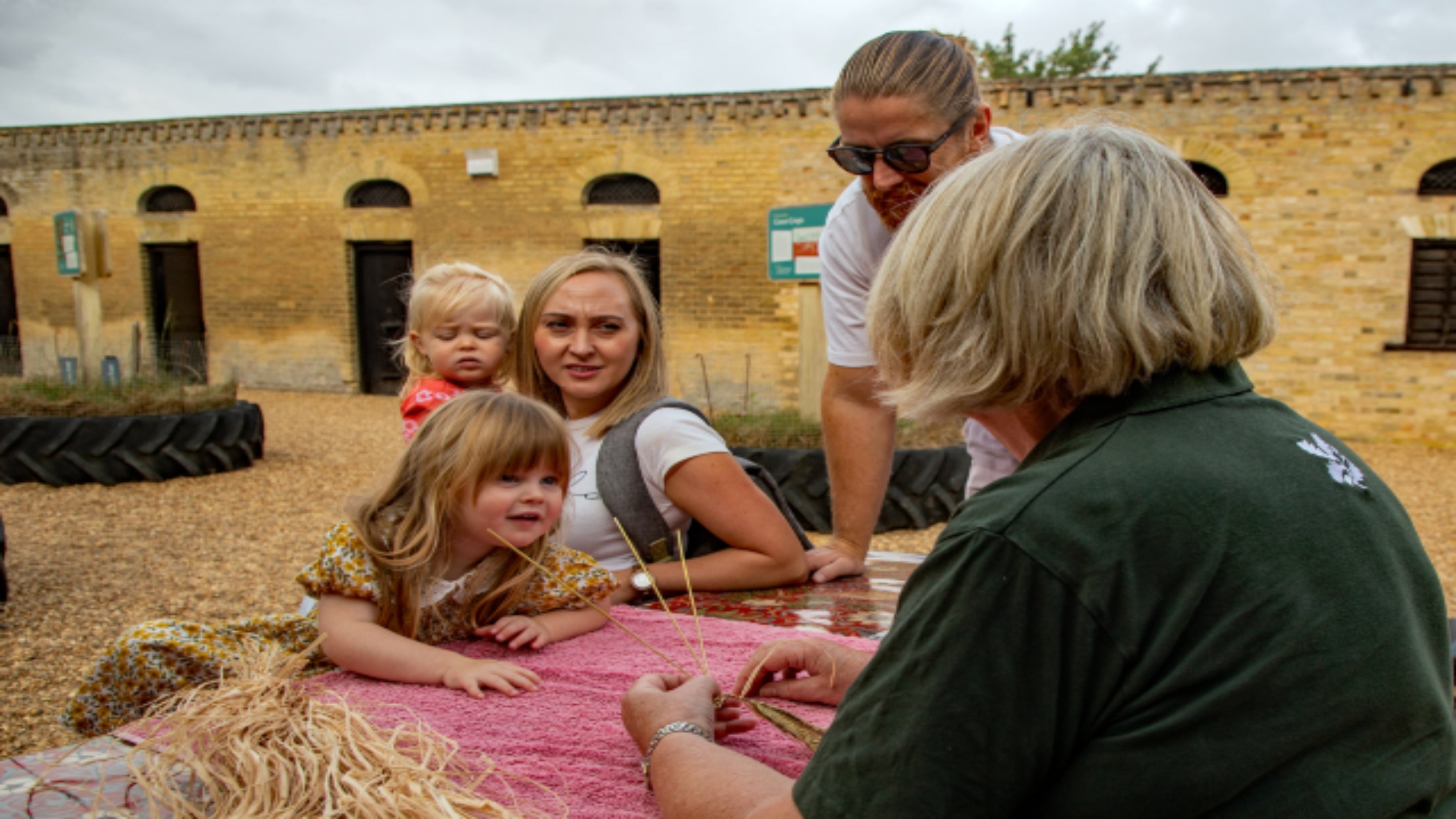 A young visitor to Wimpole Estate smiles at a volunteer who is showing them how to make crafts