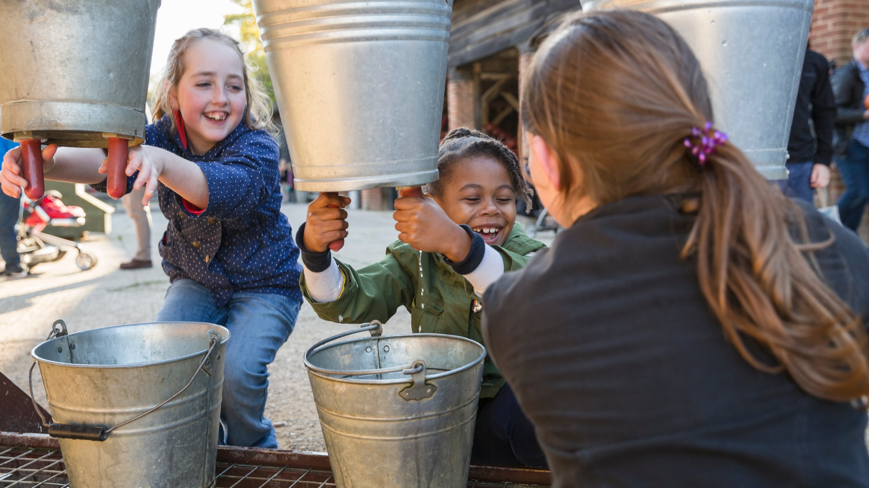 Children on Home Farm practicing milking at Wimpole Estate, Cambridgeshire