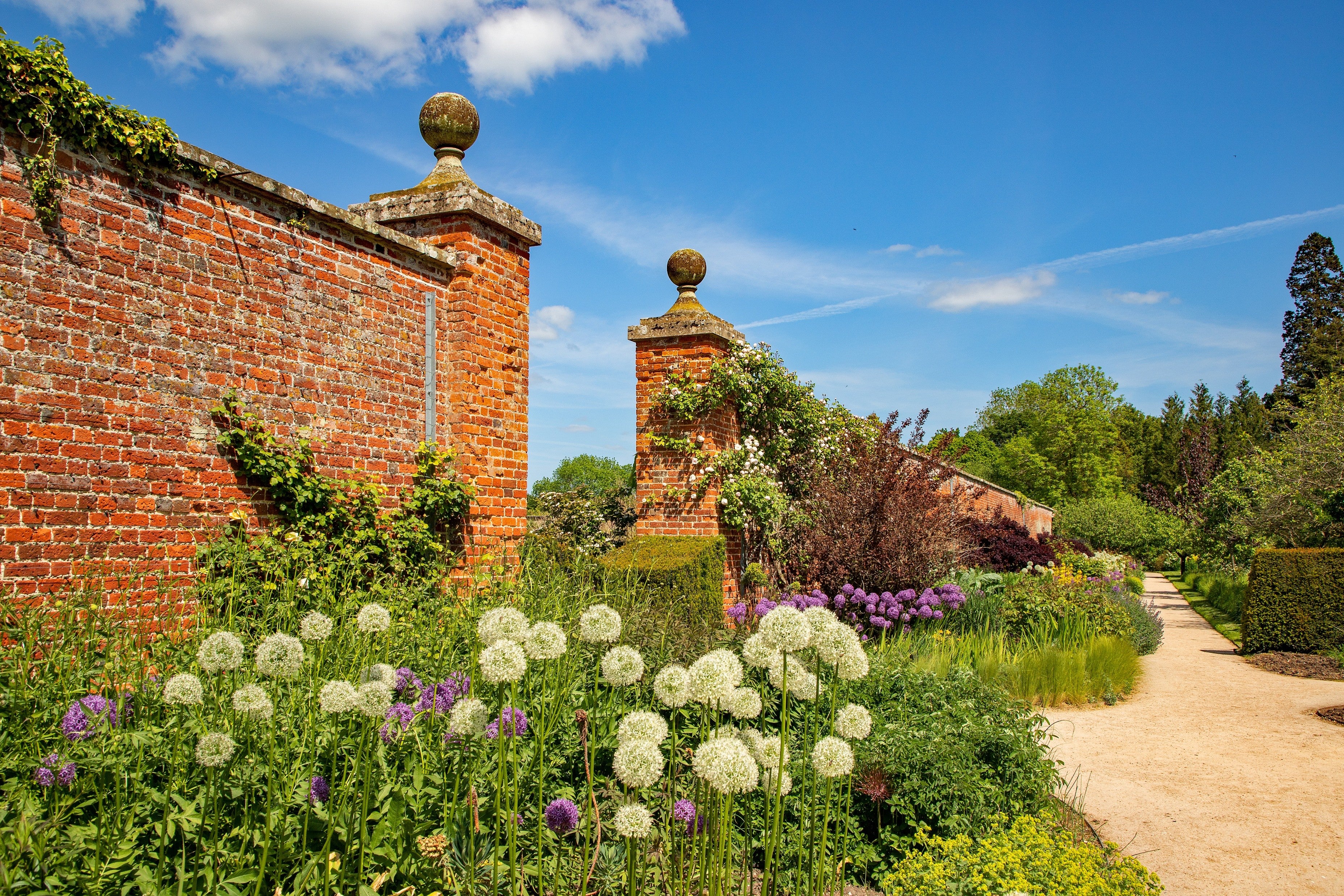 The red stone walls and entranceway to the Walled Garden at Wimpole Estate stand above beds of summer flowers