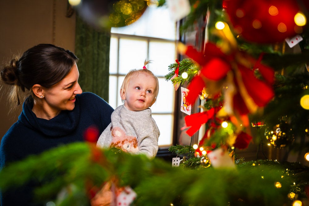 A mother and child admire a Christmas tree in Wimpole Hall, at Wimpole Estate, Cambridgeshire