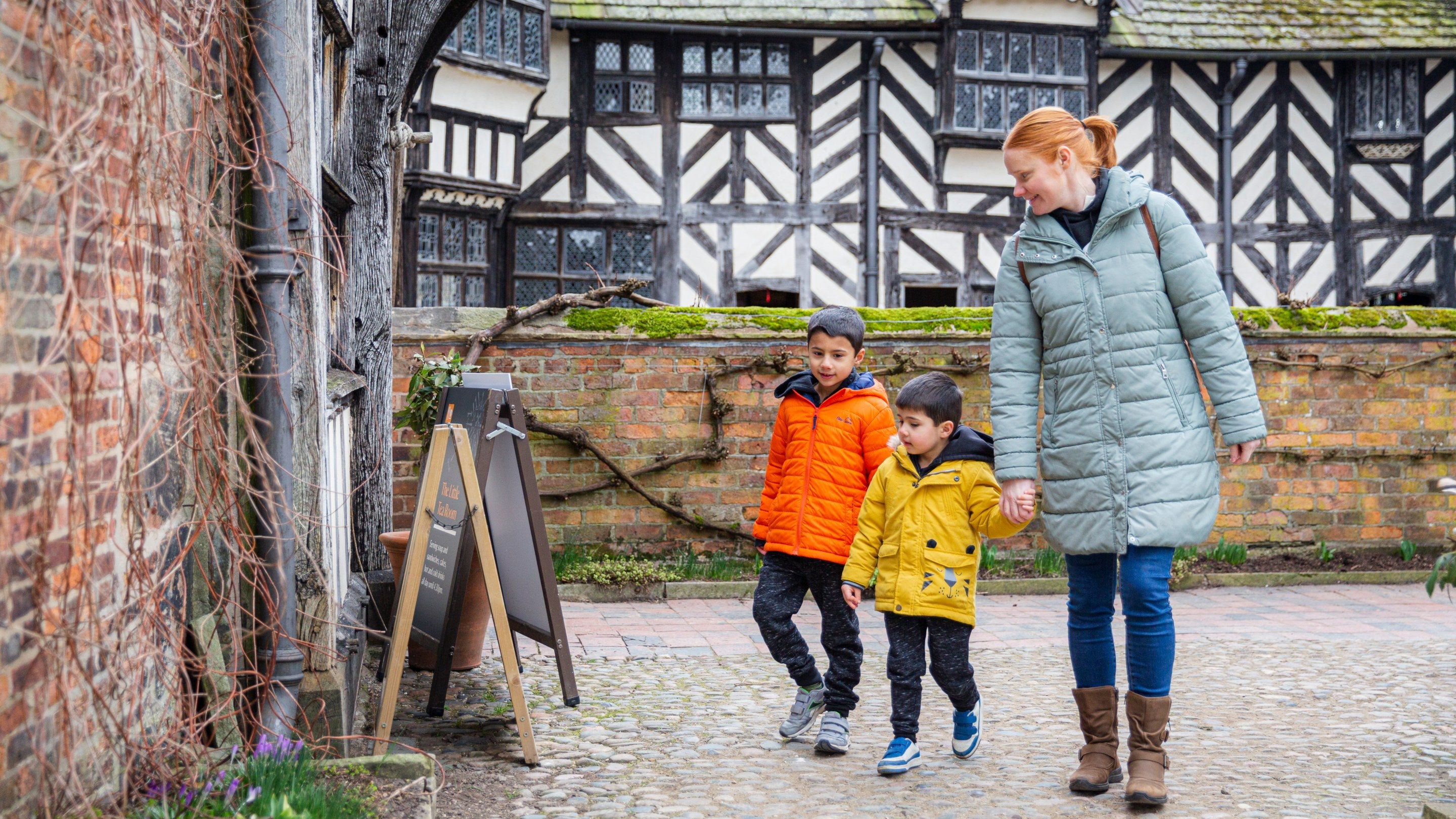A family walking around the exterior of Little Moreton Hall, Cheshire