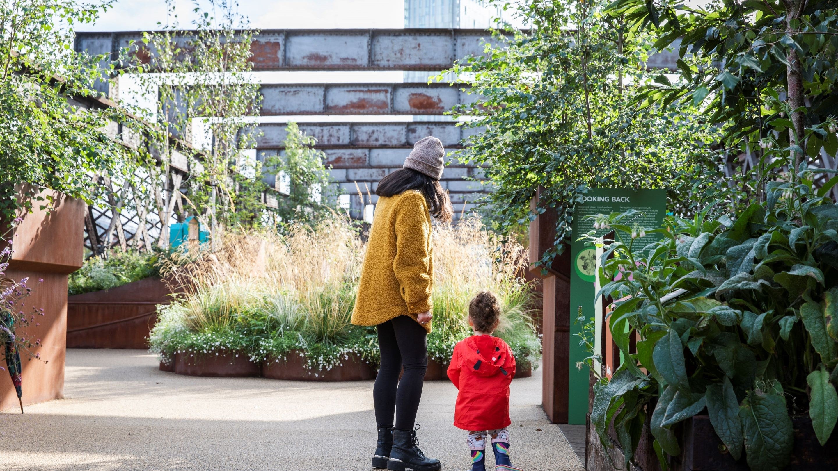 A parent and child wearing colourful coats explore Castlefield Viaduct.