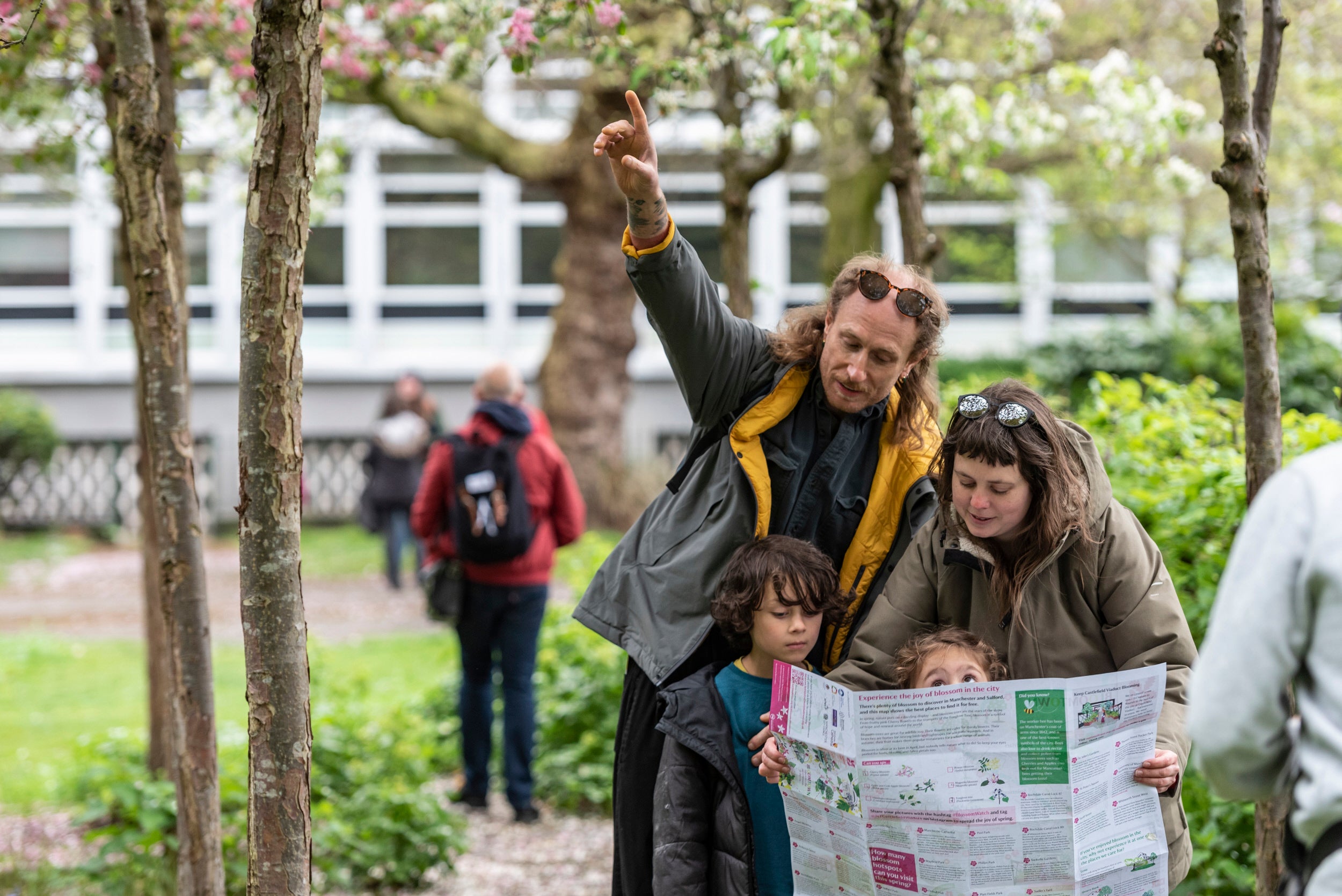 A woman and a man with their little boy and girl looking at a large colourful map in a park