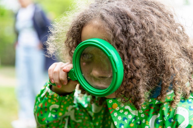 A little girl looking through a magnifying glass
