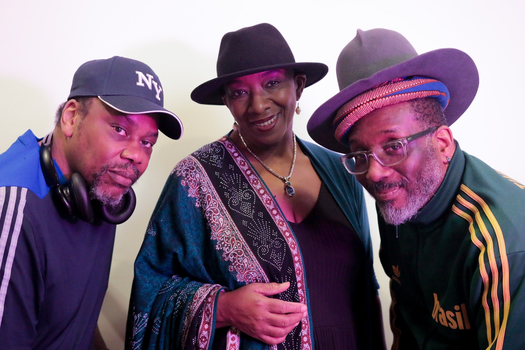Performer Shirley May wearing a black hat flanked by musicians