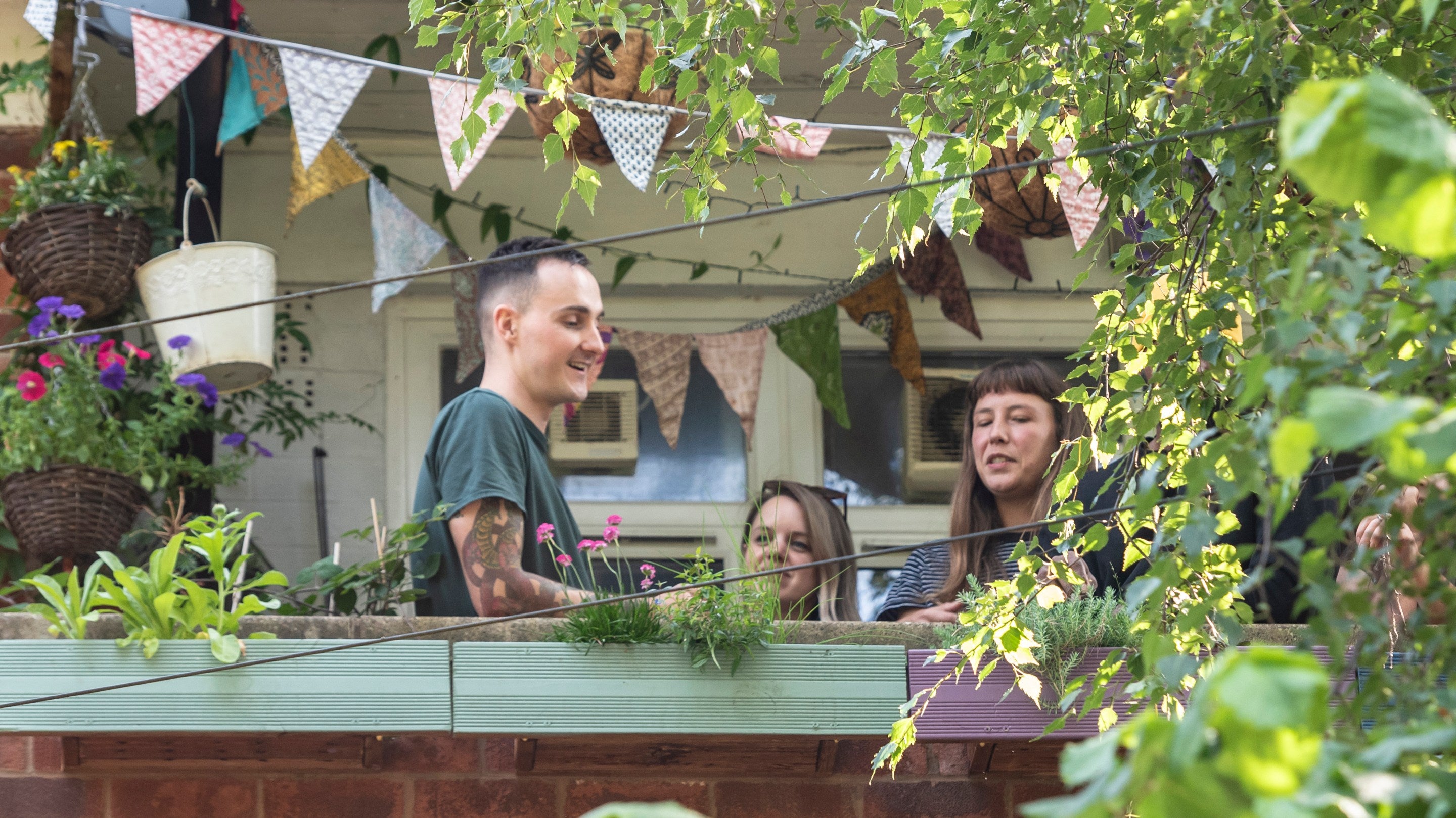 Balcony from the 2024 Sky Gardening Challenge Pilot, with lots of greenery and bunting.