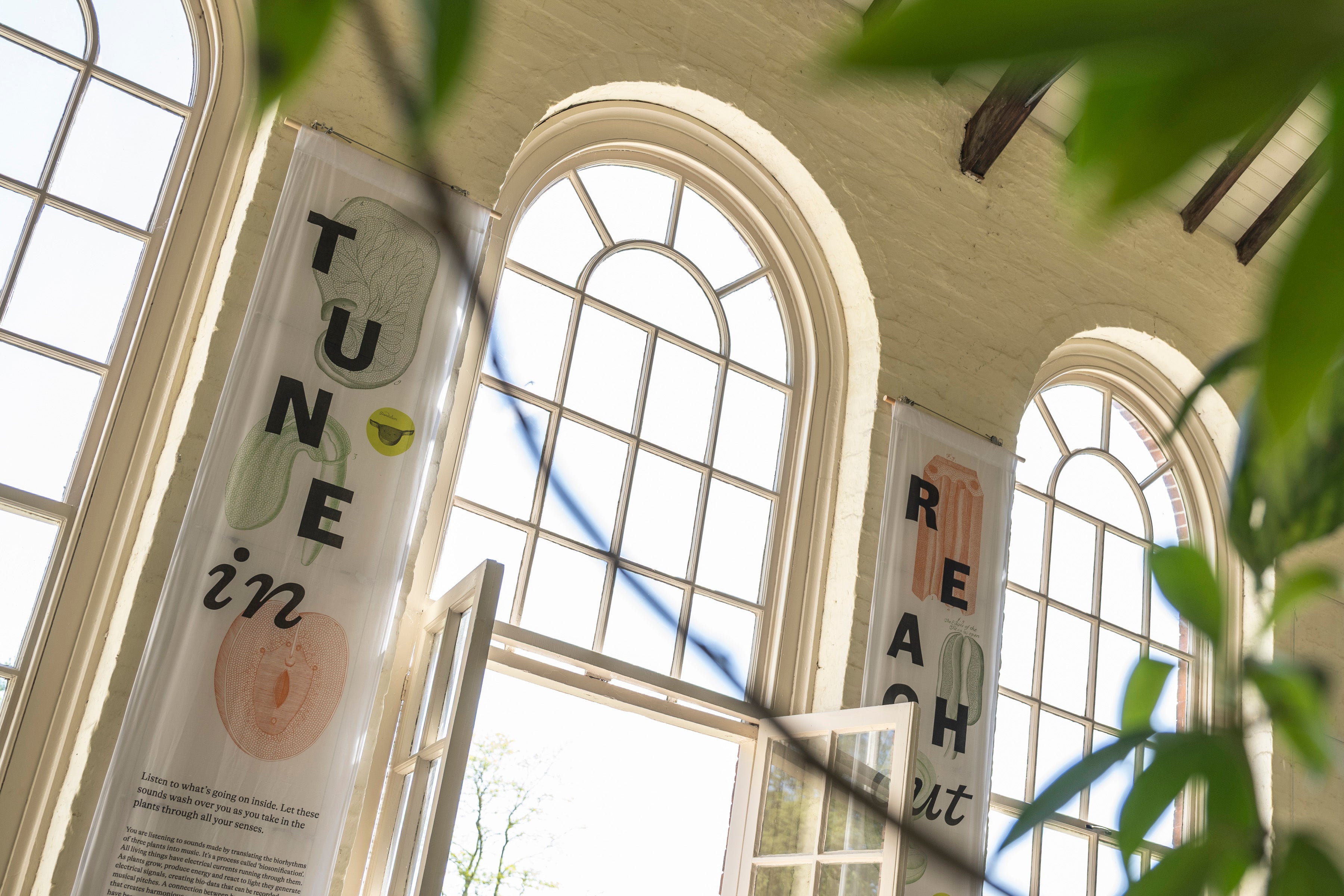 Two large cloth banners hang from the ceiling of The Orangery which read "Tune in