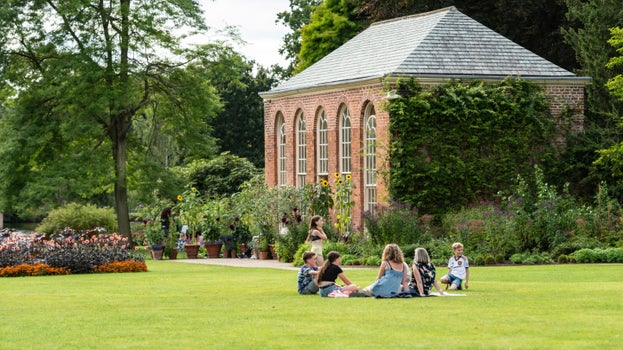A family sitting on the grass, enjoying a picnic on a sunny day.