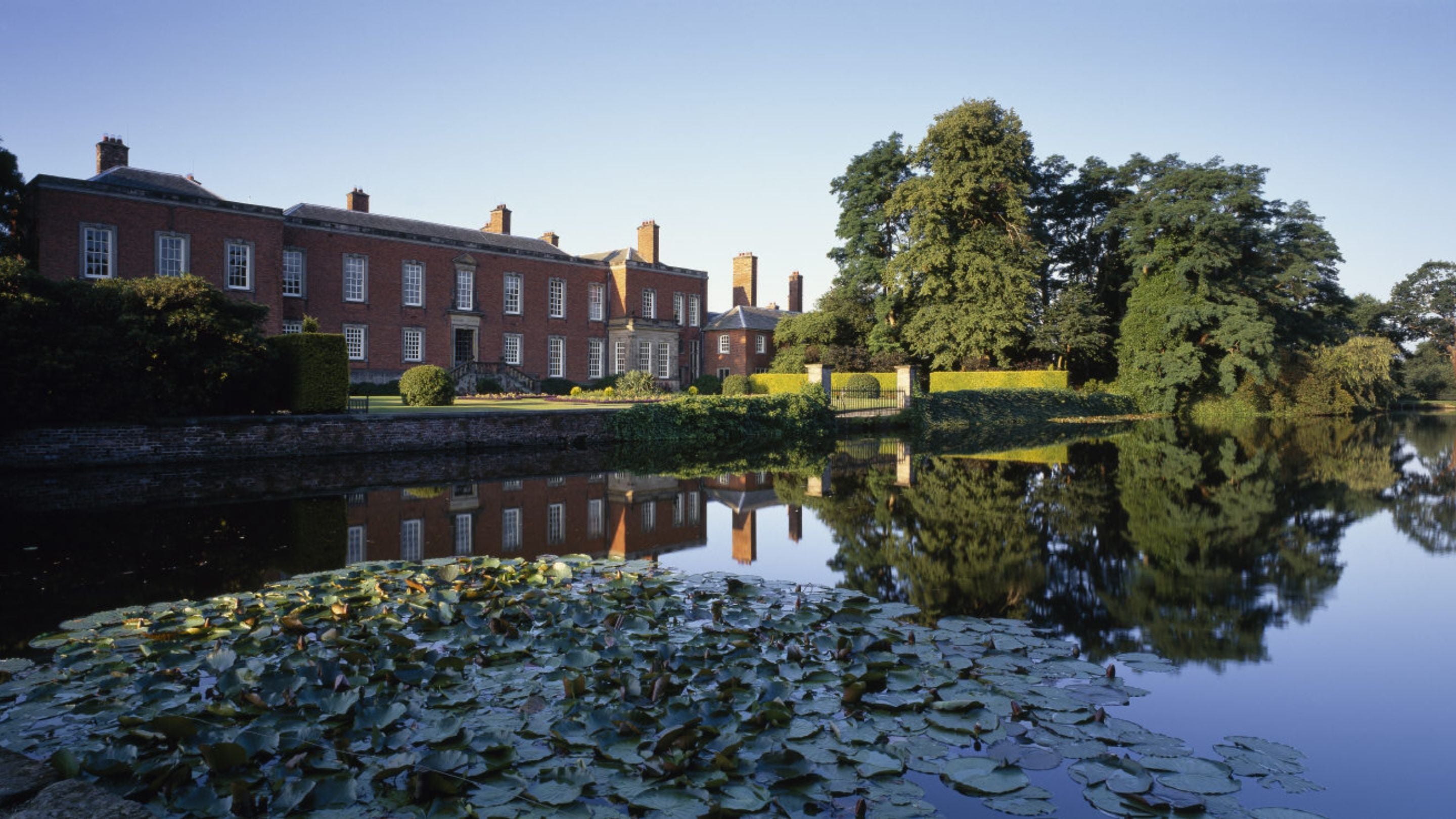 The North Front viewed across the moat at Dunham Massey. Early morning.