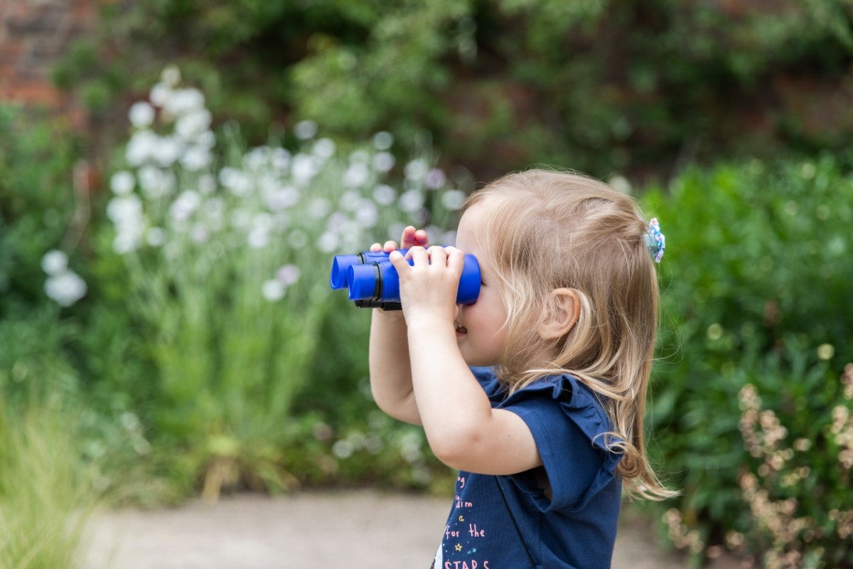 Little girl looking through binoculars in the Walled Garden at Hare Hill