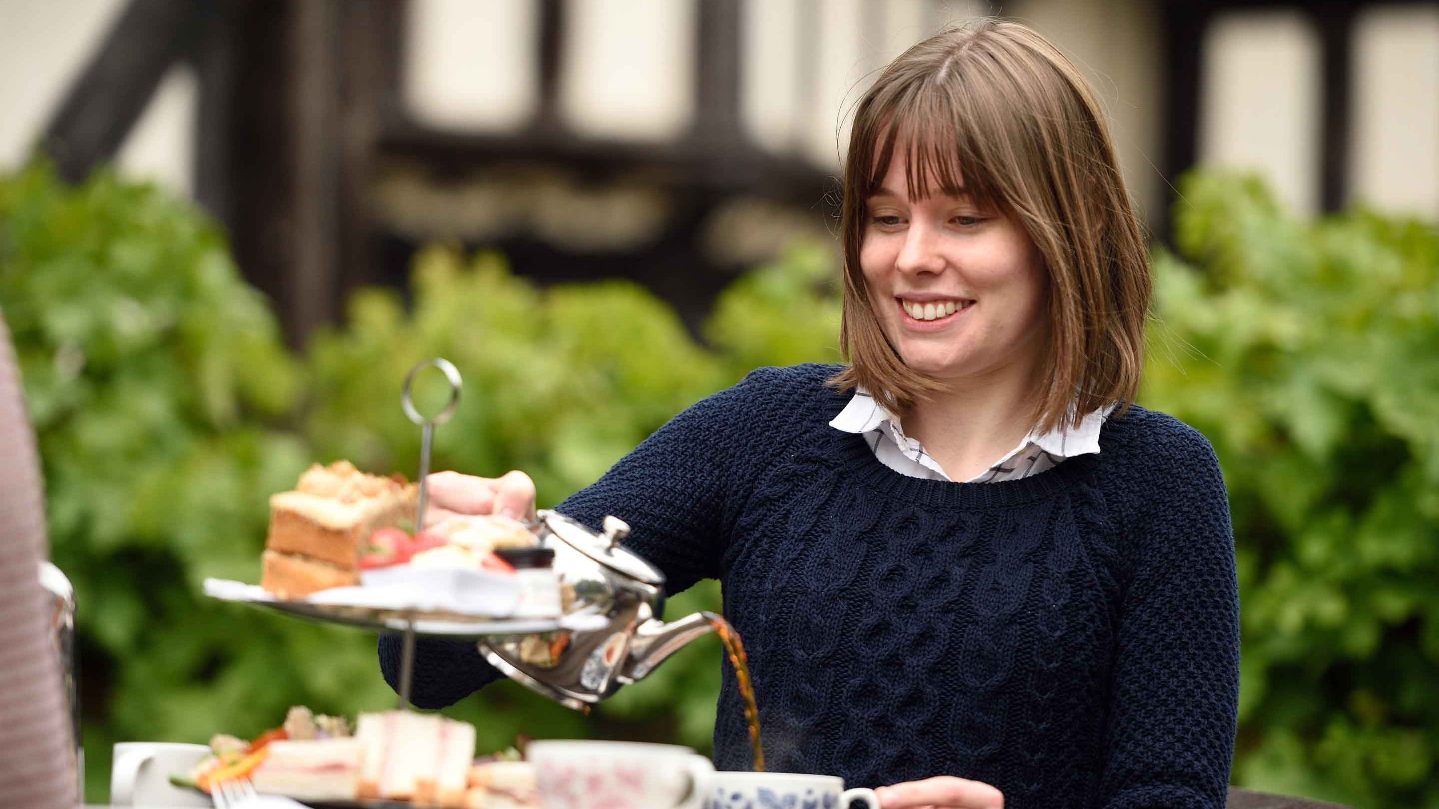Visitor enjoying afternoon tea at Little Moreton Hall, Cheshire