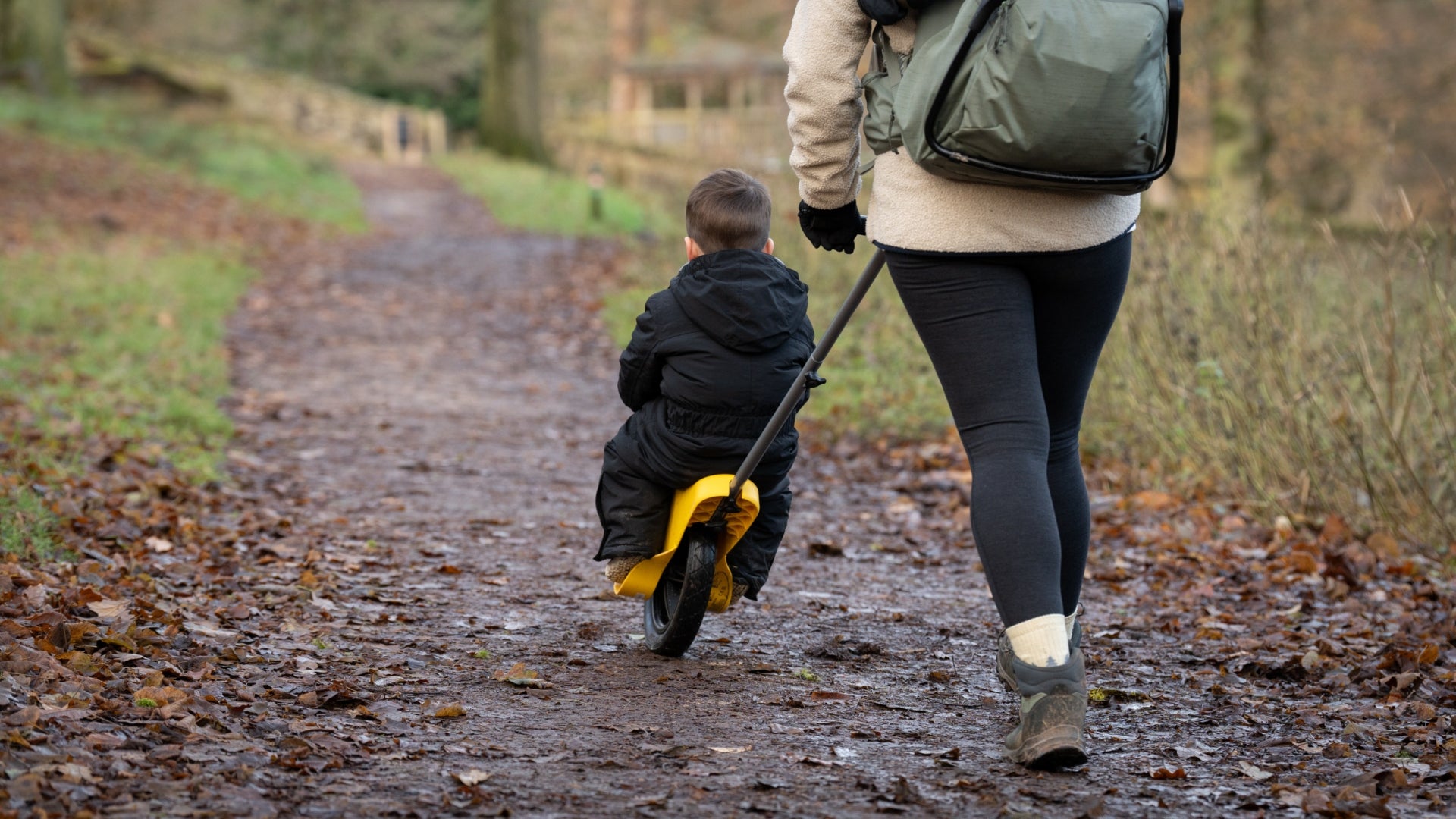 A woman wrapped up warm, wearing hiking boots pushes her son along a path on a winter walk at Lyme, Cheshire.