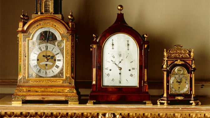 Three ornate clocks on top of a mantlepiece.
