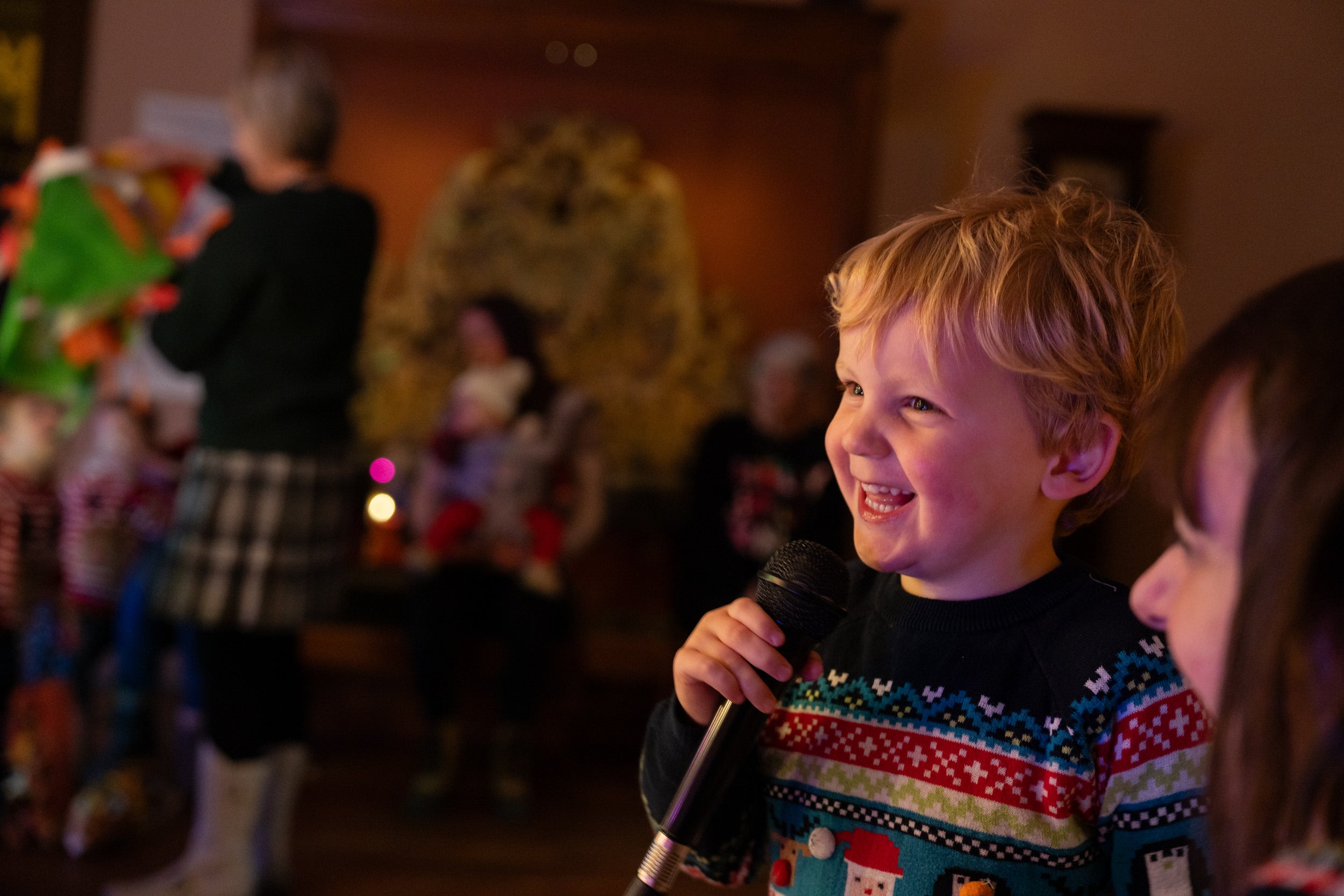 A little boy grins as he holds a microphone next to his family, singing karaoke in the State Bedroom at Lyme.