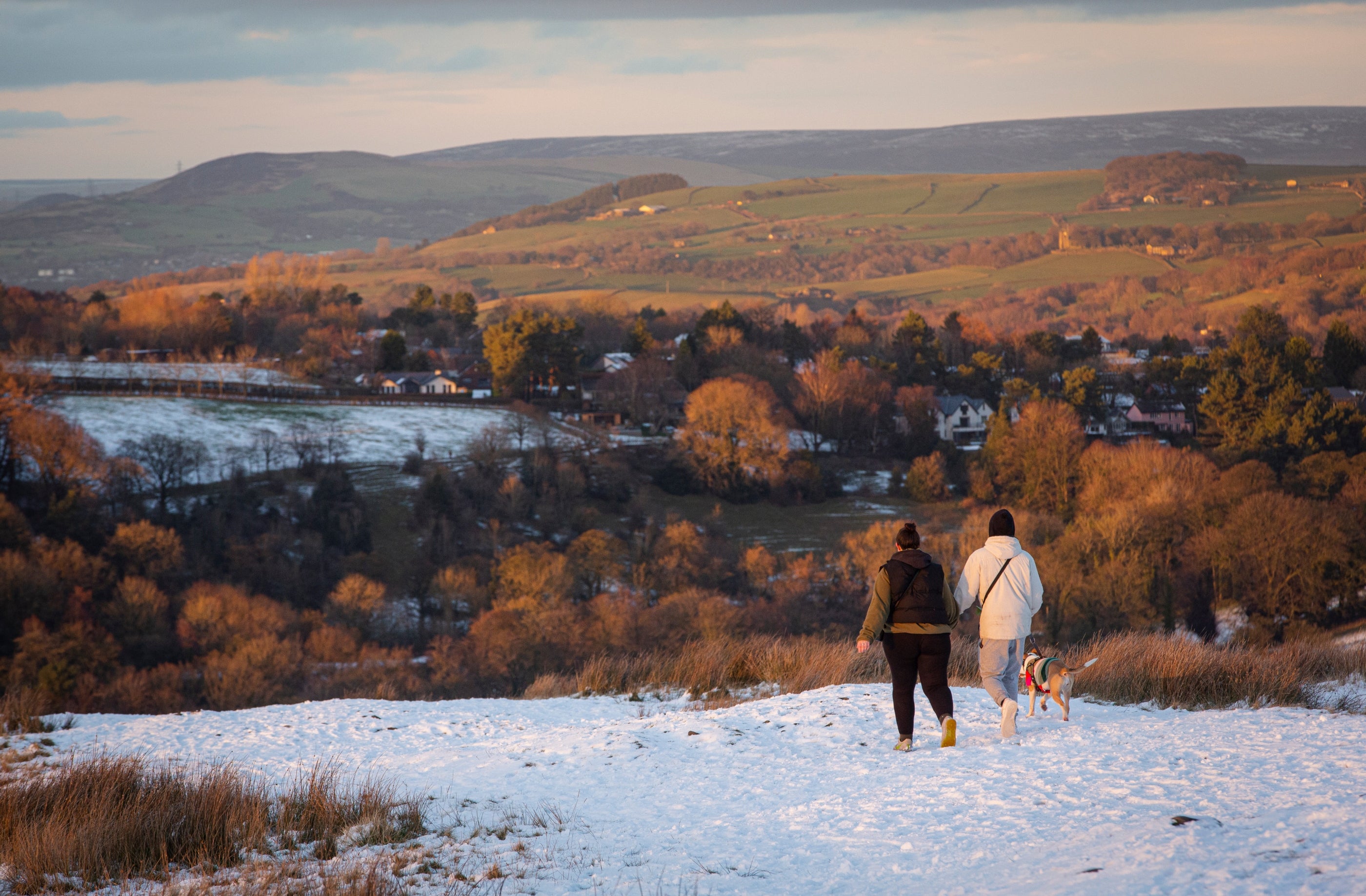 Visitors walking in the parkland at sunset surrounded by an autumnal snow-covered landscape