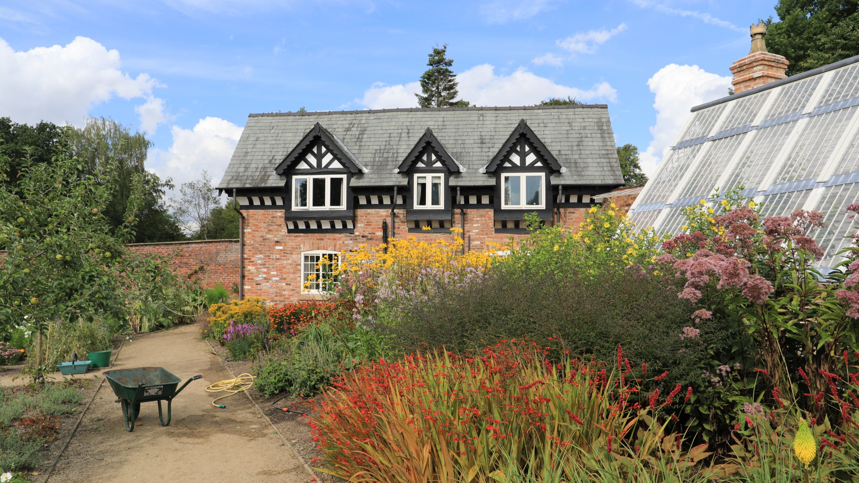Gardener's cottage in the upper garden, surrounded by summer planting at Quarry Bank Mill, Cheshire