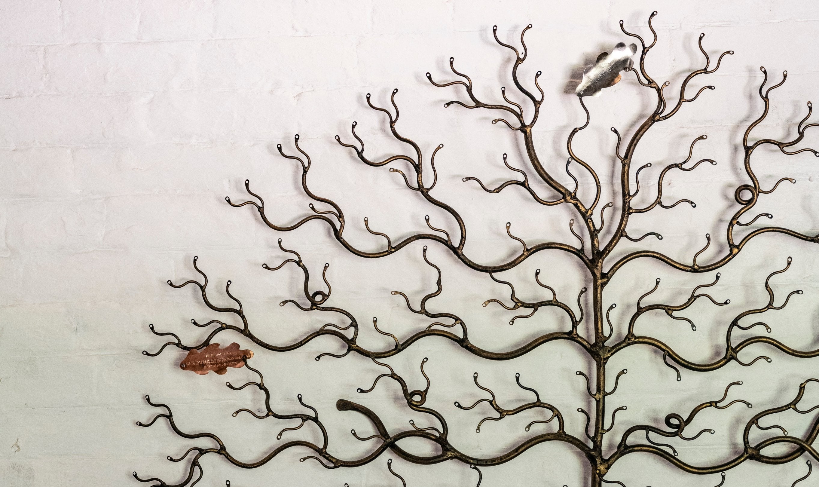 a white brick wall with a metal tree displayed