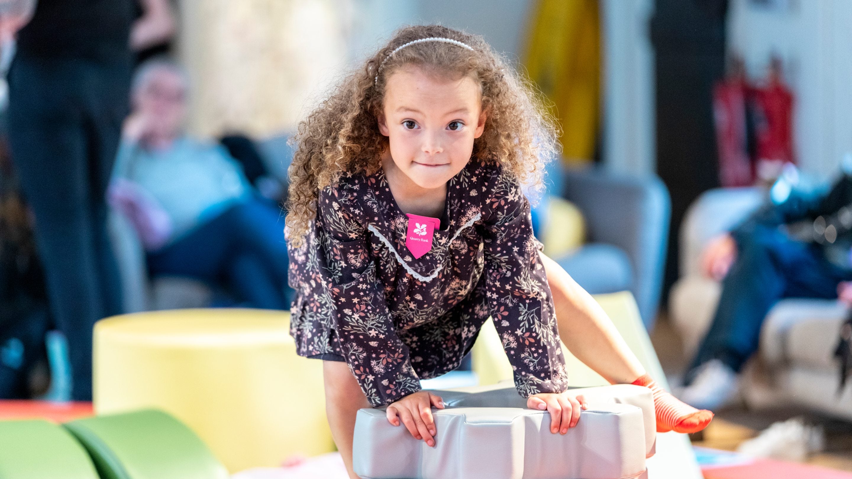 A little girl climbing over a piece of soft play looking towards the camera