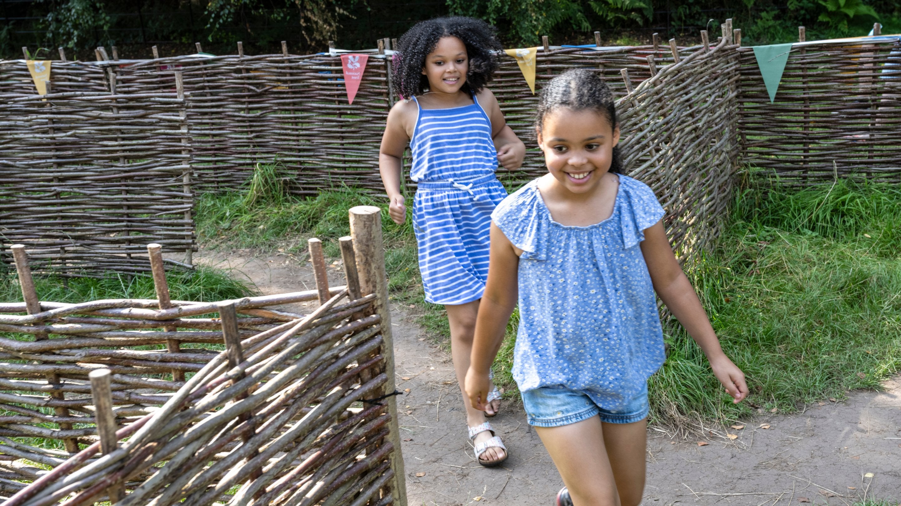 Two girls in blue outfits running through a maze