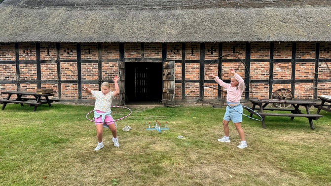 Family visitors in summer on an Old Hall Open Day with the Cruck Barn in the background, Tatton Park, Cheshire