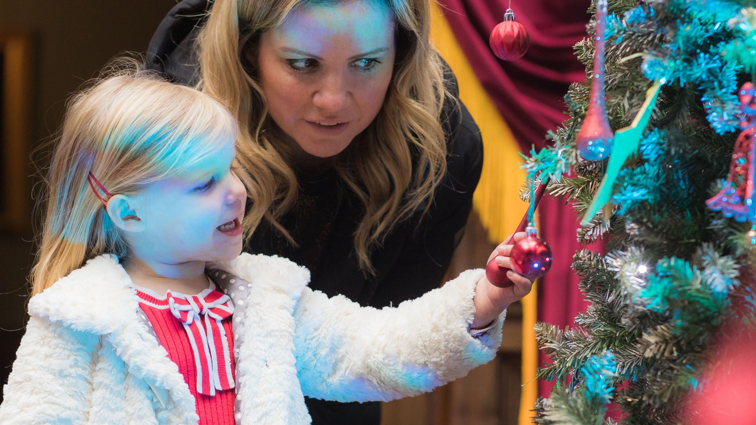 A child and mother looking at the decorations on a Christmas tree at Tatton Park, Cheshire