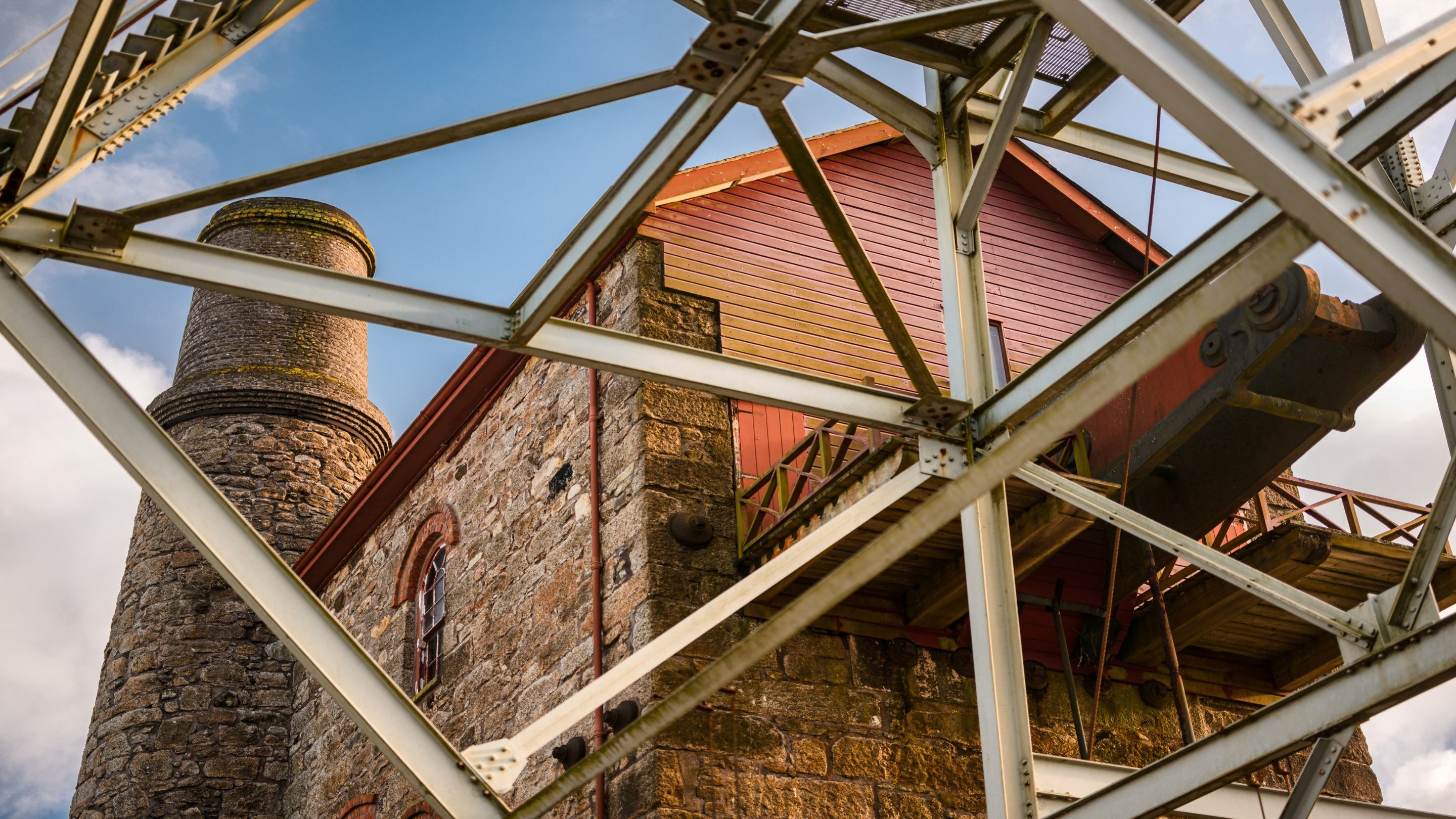 Steel frame in front of an old brick building with a chimney