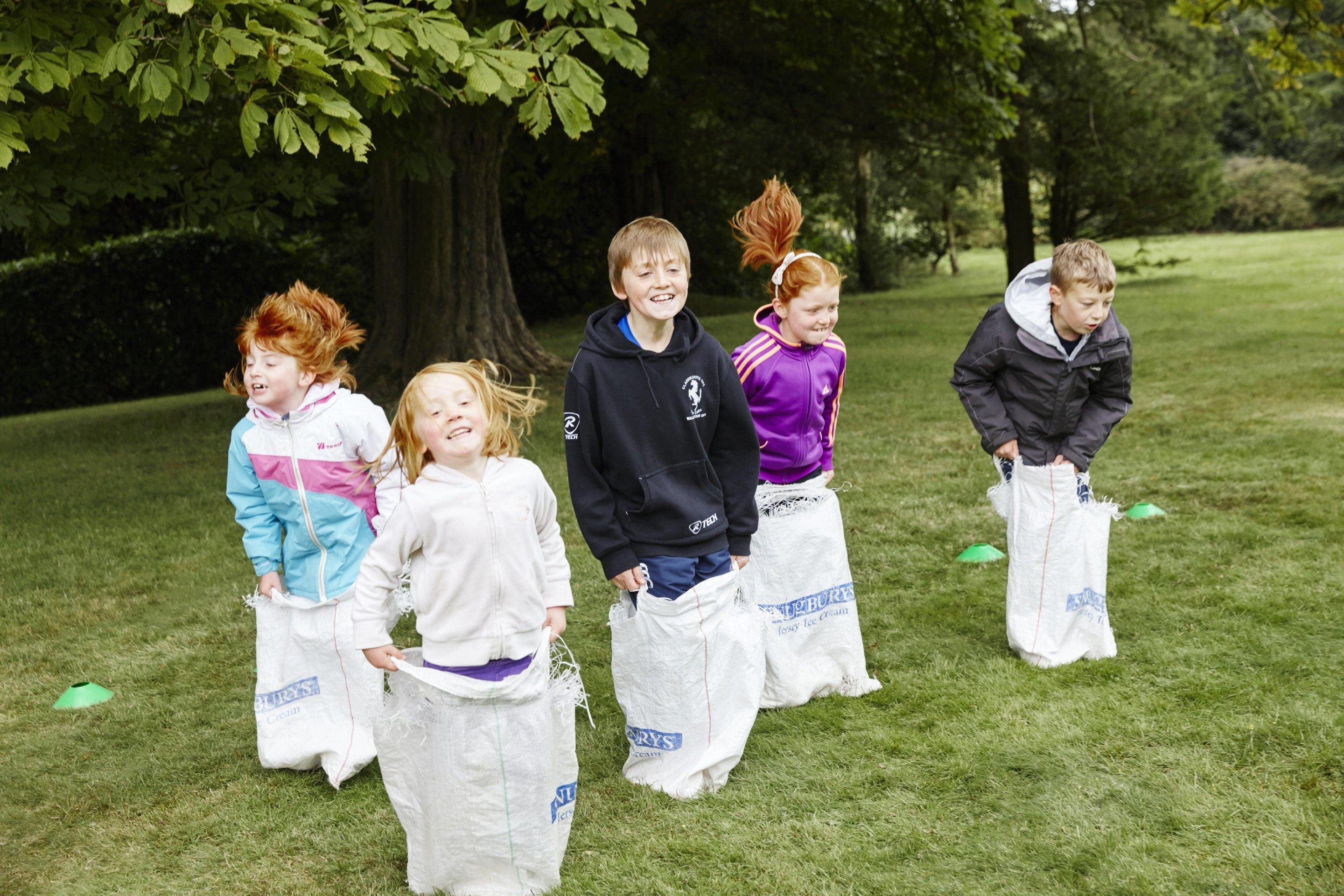 Children in a sack race in summer in a National Trust garden
