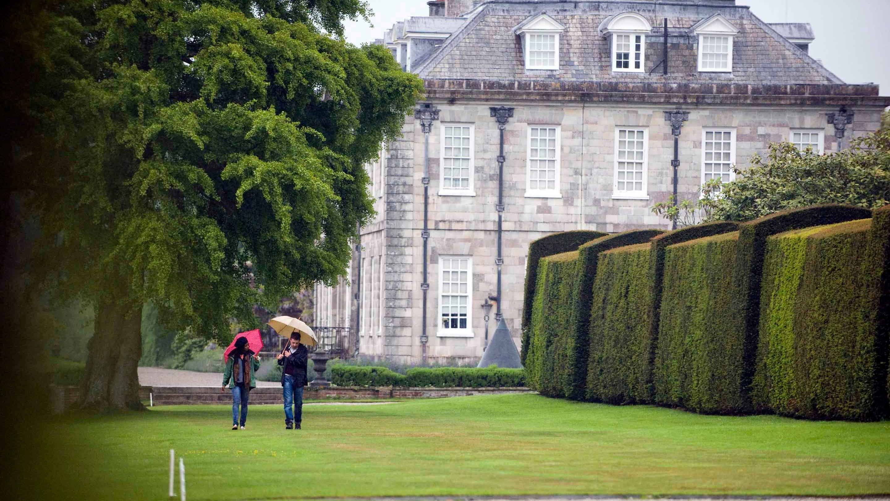 Visitors walking in rain at Antony with the house in the background
