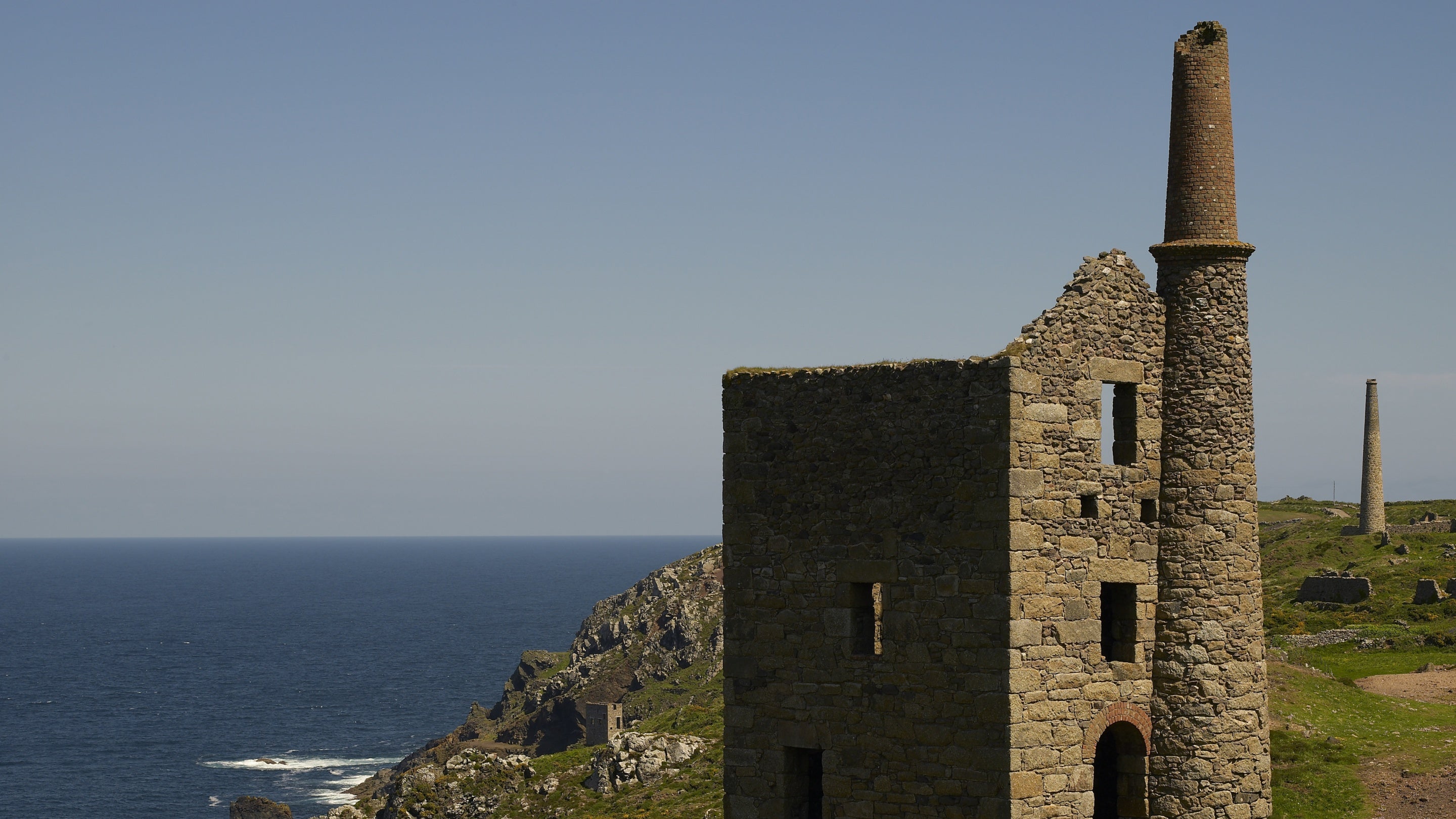 The abandoned mine engine house of West Wheal Owles, with the Crowns engine houses in the background, at Botallack on Tin Coast, Cornwall