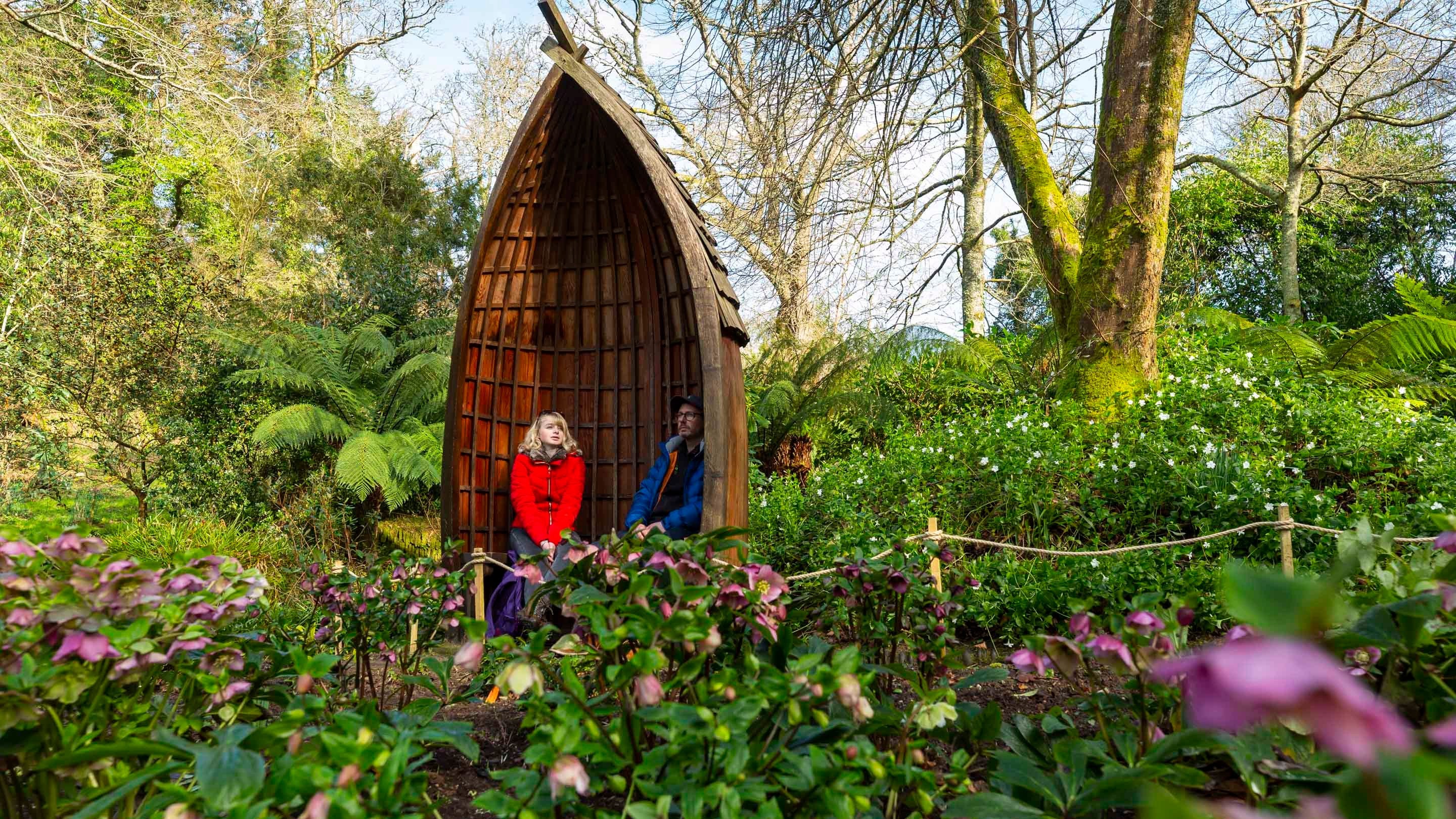 Two people using the boat seat surrounded by flowers and shrubs