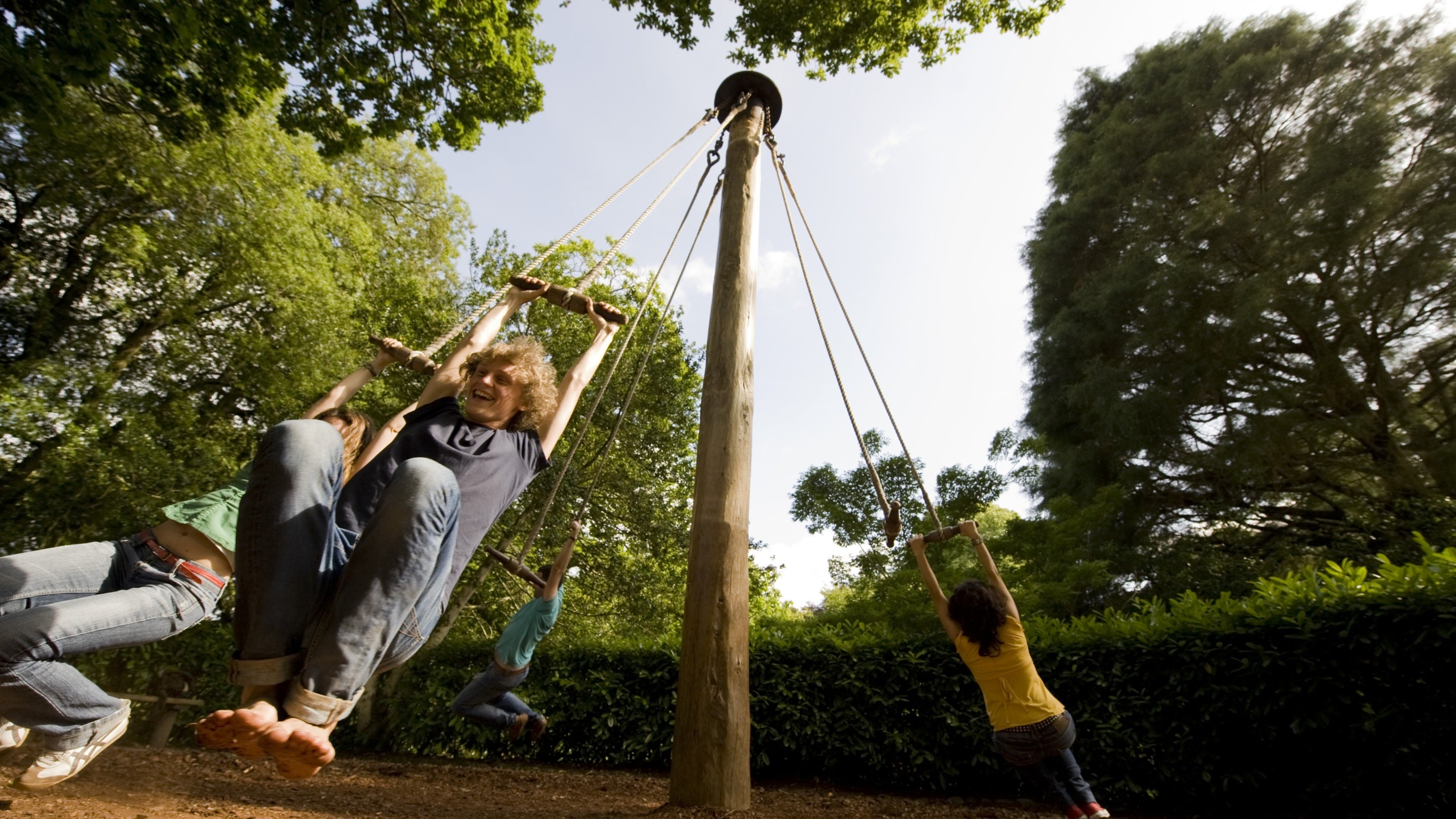 Visitors playing on the Giant's Stride rope swing in the garden at Glendurgan, Cornwall