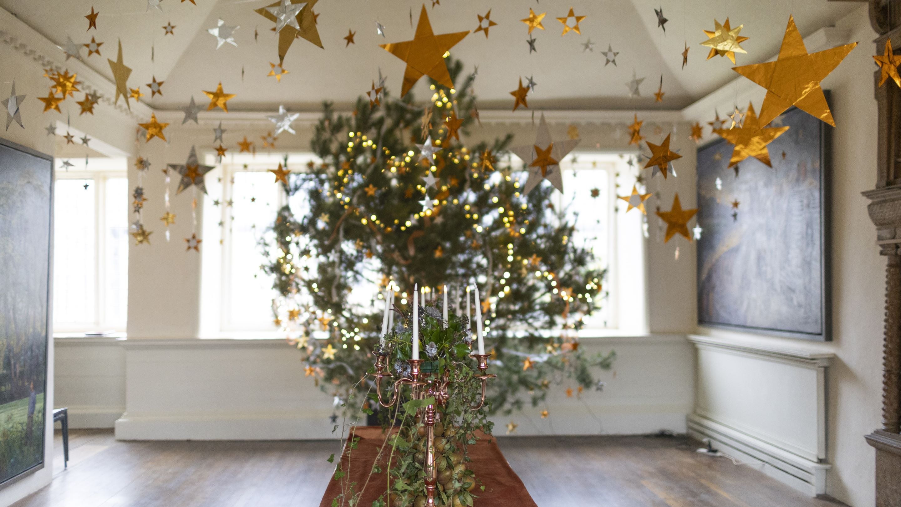 A decorated Christmas tree in a white room hung with gold stars
