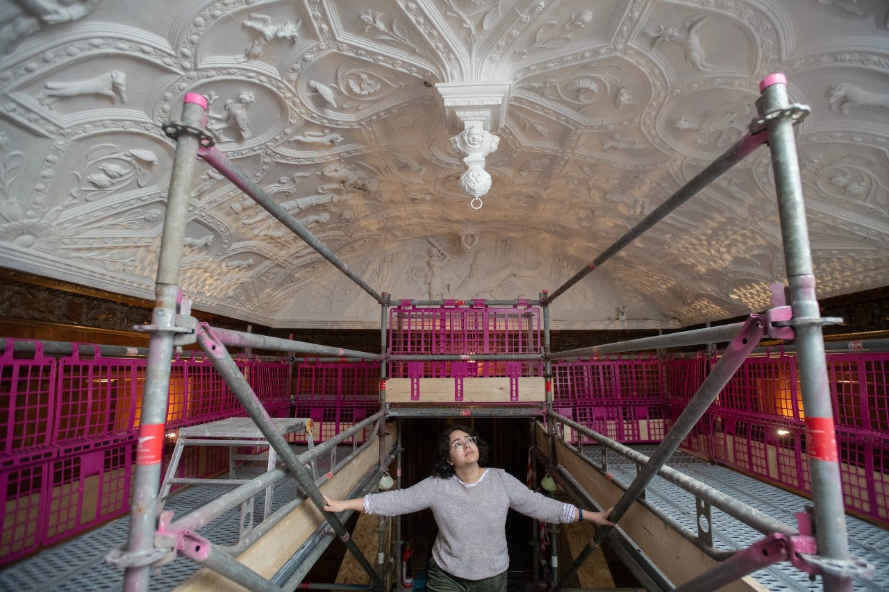 A visitor walking up the scaffold steps onto the scaffold in the Long Gallery at Lanhydrock to view the Jacobean ceiling
