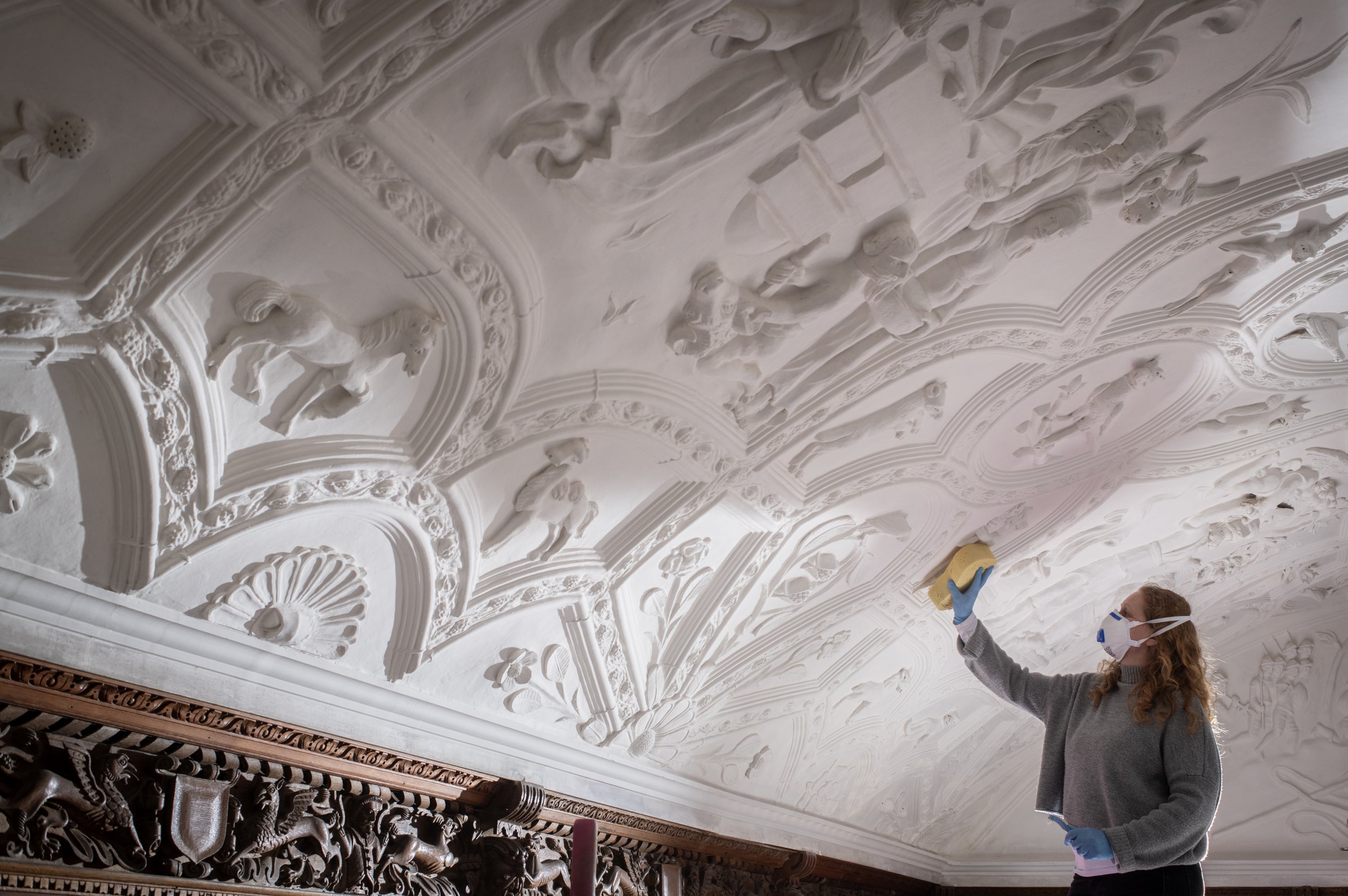 Conservator using a sponge cleaning the Long Gallery ceiling at Lanhydrock