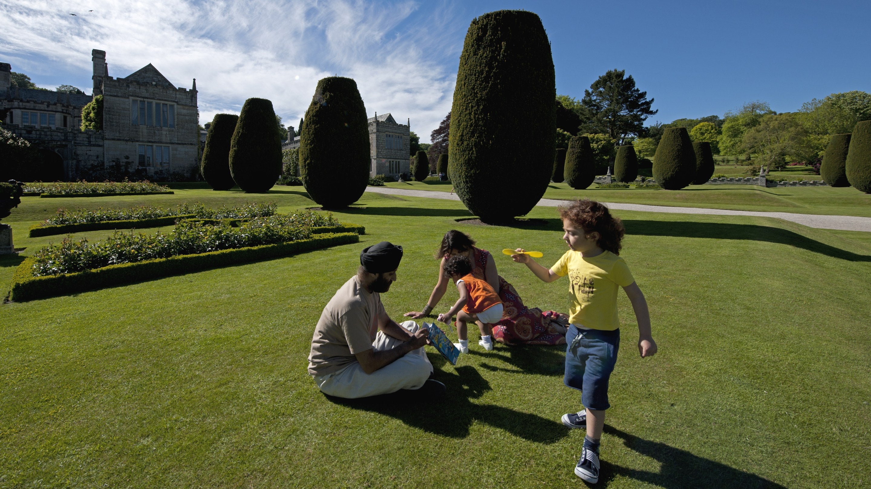 Family in the garden at Lanhydrock, Cornwall with children playing and adults seated