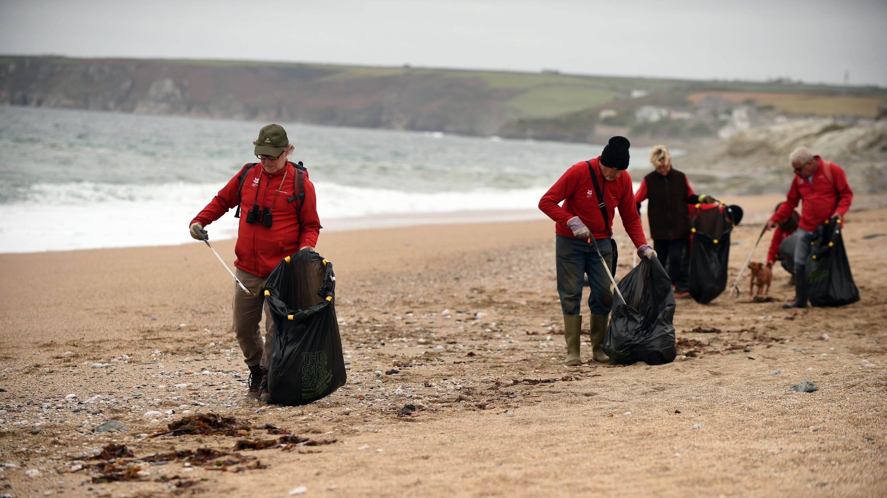 A group of volunteers picks up litter from the beach at Penrose, Cornwall