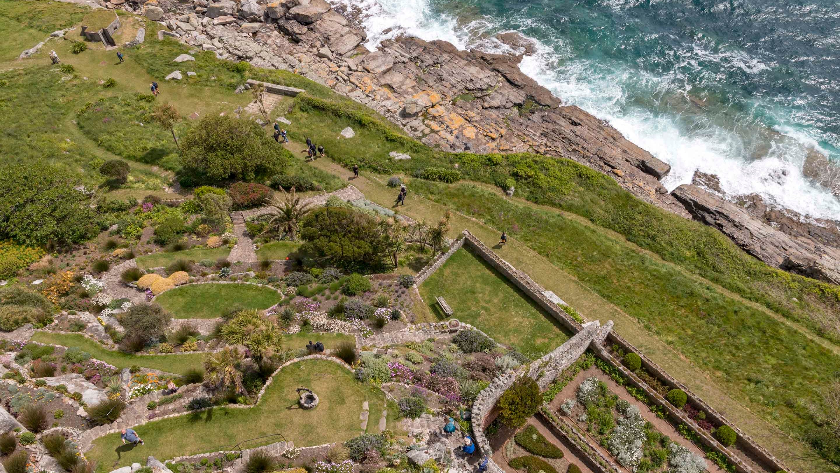 A bird's eye view of the gardens, cliffs, and sea at St Michael's Mount, Cornwall
