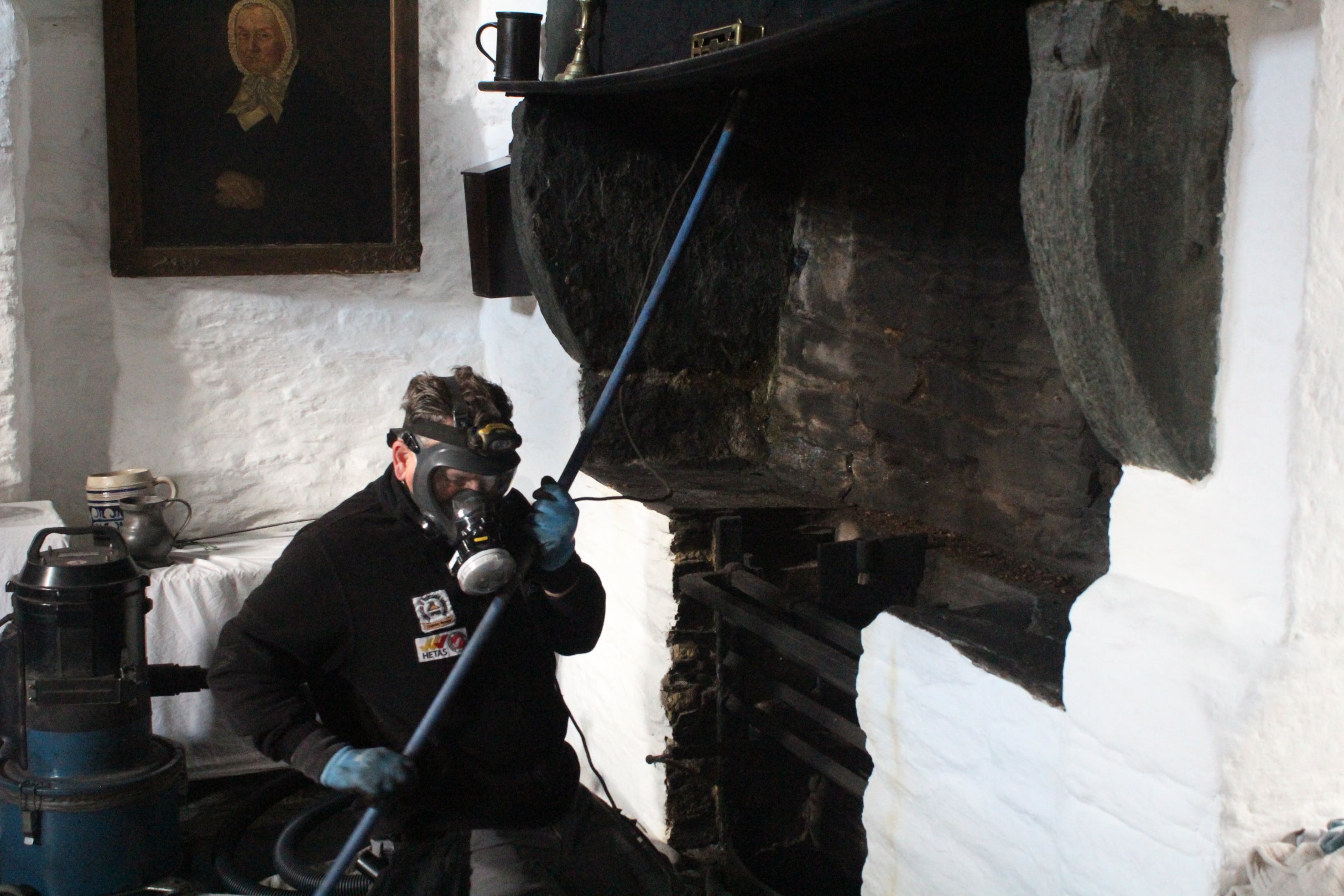 A chimney sweep carrying out a flue camera survey at the hall fire in Tintagel Old Post Office
