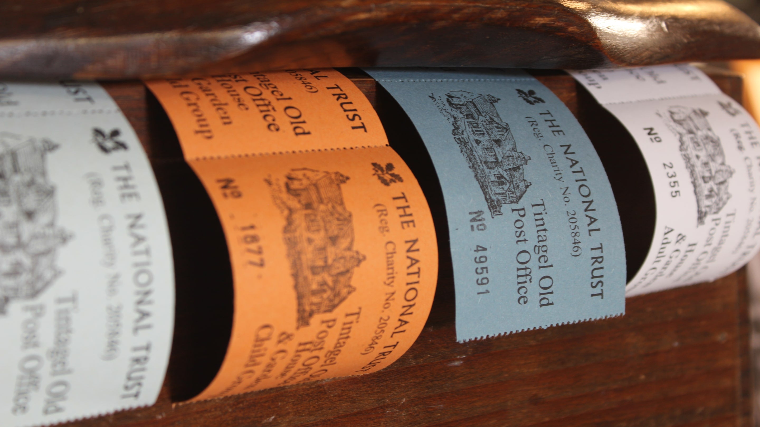 A close up of traditional paper admission ticket rolls at a wooden till.